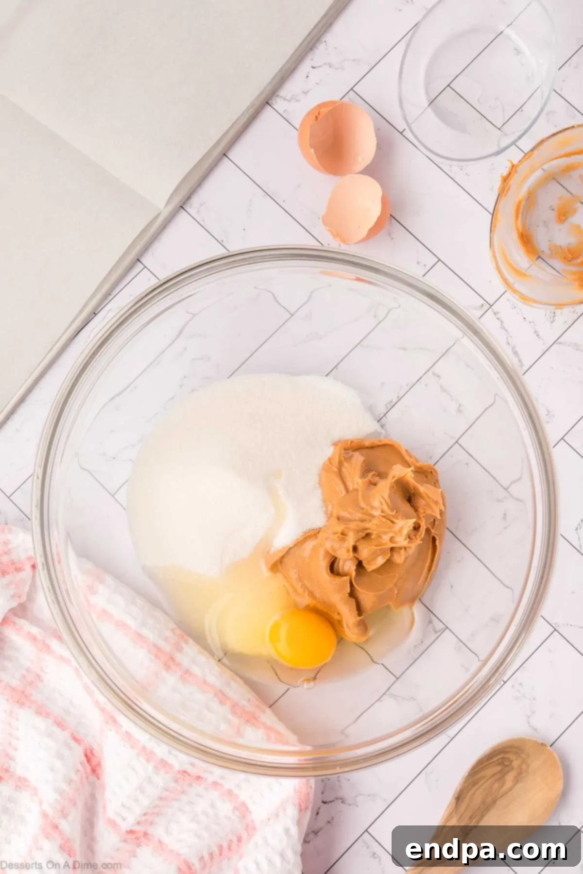 Mixing bowl containing peanut butter, sugar, and an egg, ready to be combined.