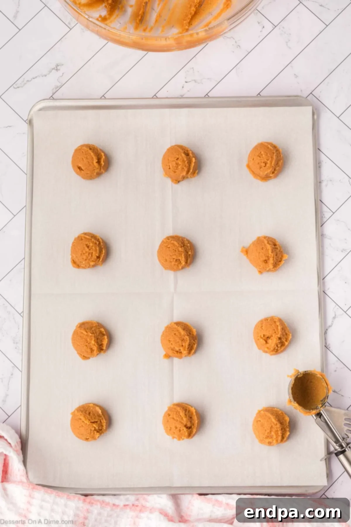 Cookie dough balls evenly spaced on a parchment-lined baking sheet.