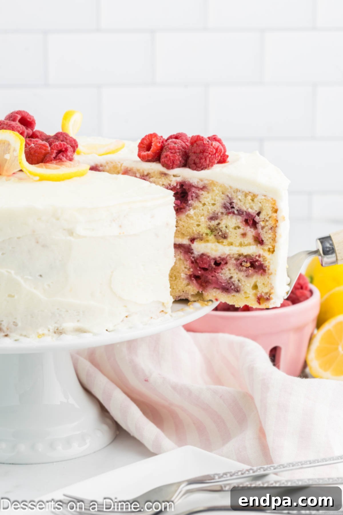 Lemon Berry Bliss 2 Lemon raspberry cake being sliced, revealing beautiful layers of cake and frosting with raspberries throughout.