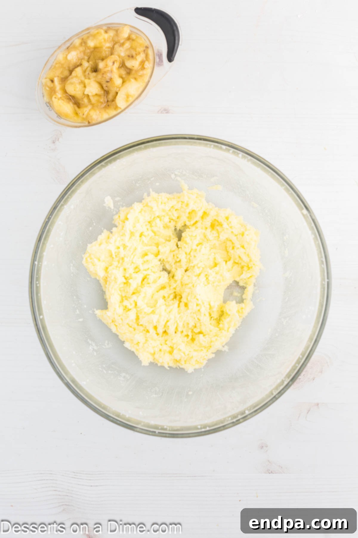 Softened butter and granulated sugar being creamed together in a mixing bowl until light and fluffy.