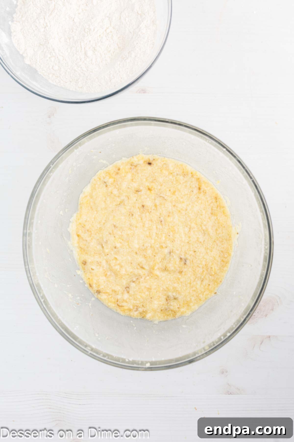 Freshly mashed bananas being added to the creamed butter, sugar, and egg mixture.