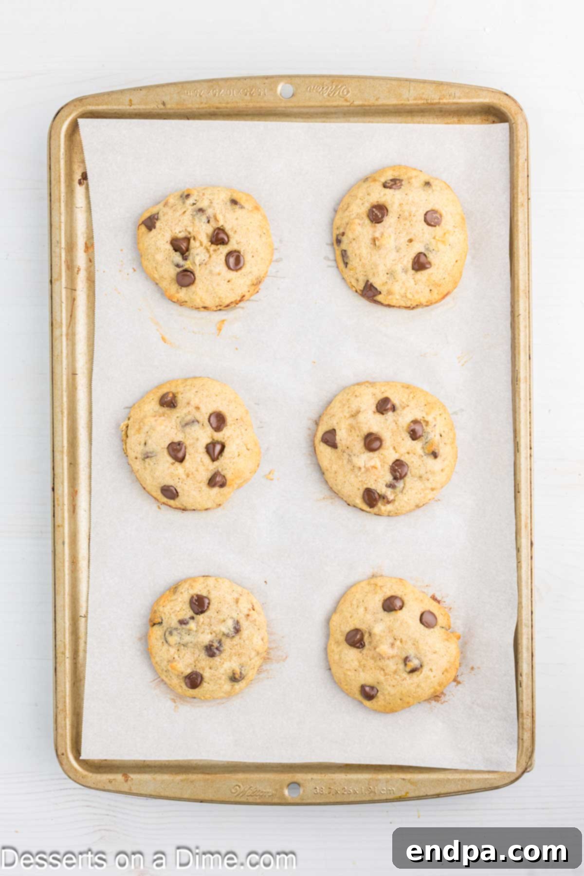 Freshly baked banana cookies cooling on the baking sheet, with lightly browned edges.