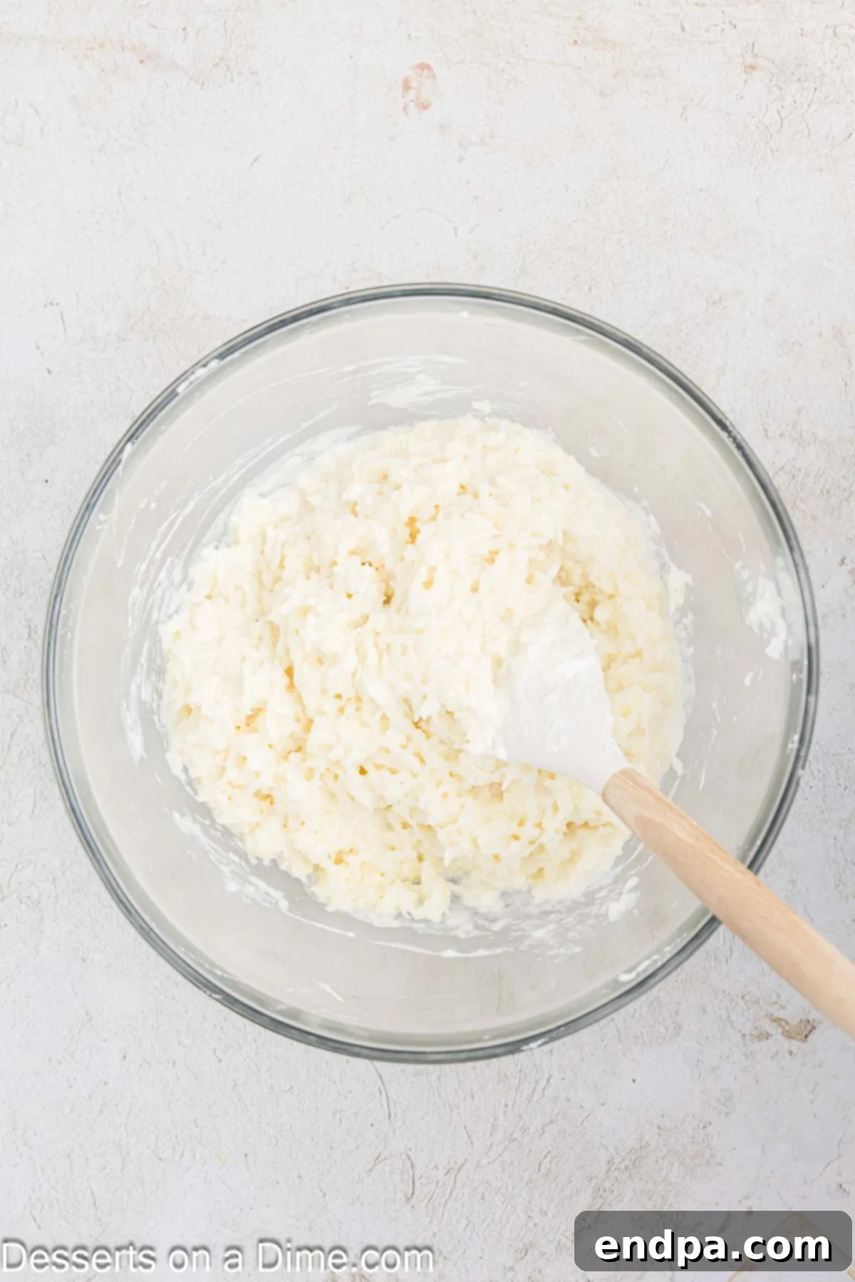 Gently folding the beaten egg whites into the coconut mixture by hand.