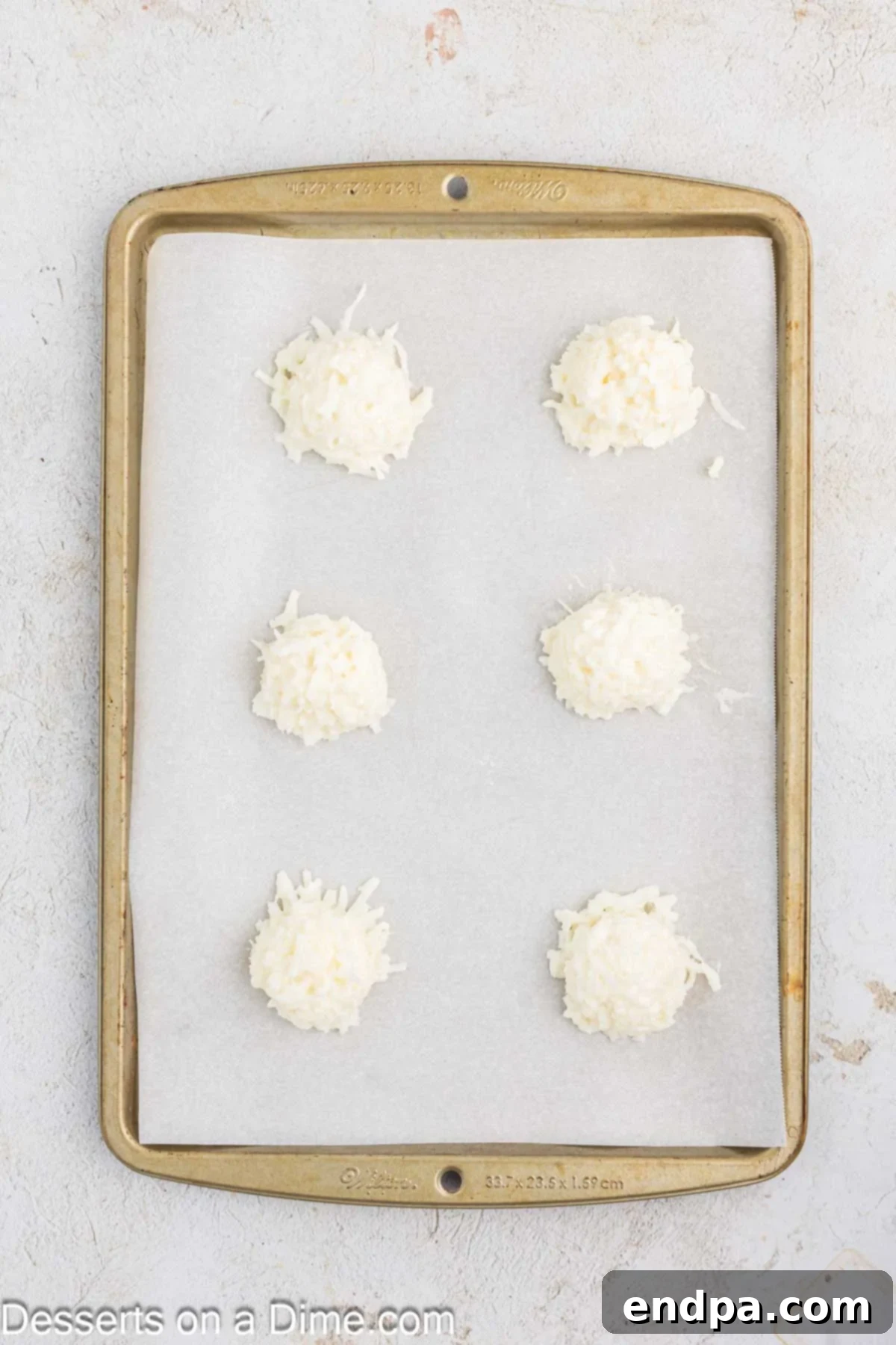 Coconut Macaroon mounds scooped onto a parchment-lined baking sheet, ready for baking.