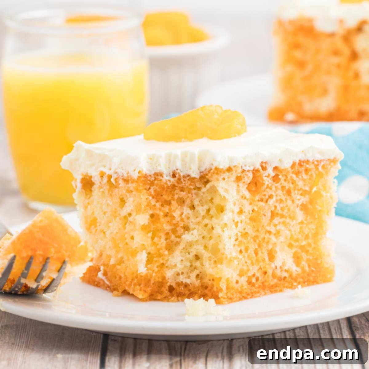 Velvet Orange Dream Cake 13 Full Orange Creamsicle Cake with a single slice removed, showing its layers and creamy frosting, garnished with mandarin oranges.