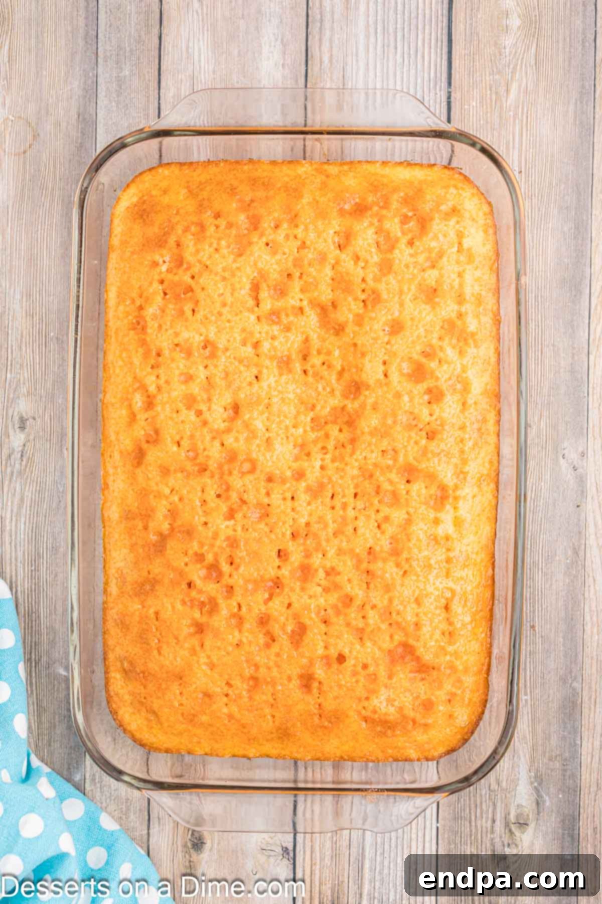 Velvet Orange Dream Cake 8 Orange jello mixture poured over the poked cake, allowing the liquid to soak into the holes and infuse the cake.