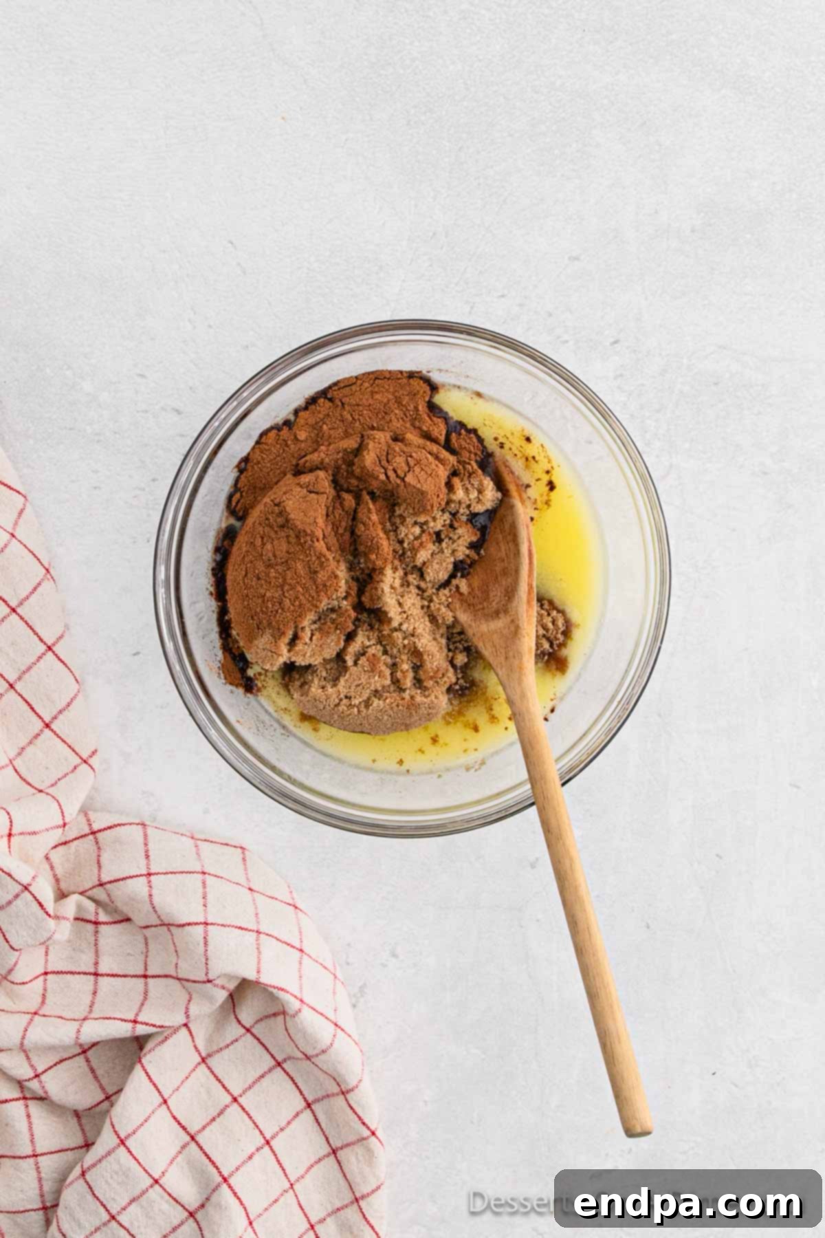 A bowl containing a mixture of melted butter, brown sugar, and ground cinnamon, ready for the filling.