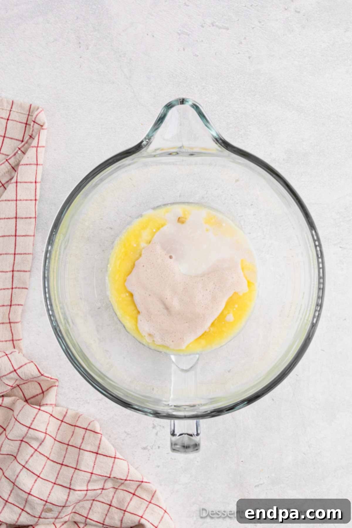 A measuring cup containing warm water and active dry yeast, beginning to activate.