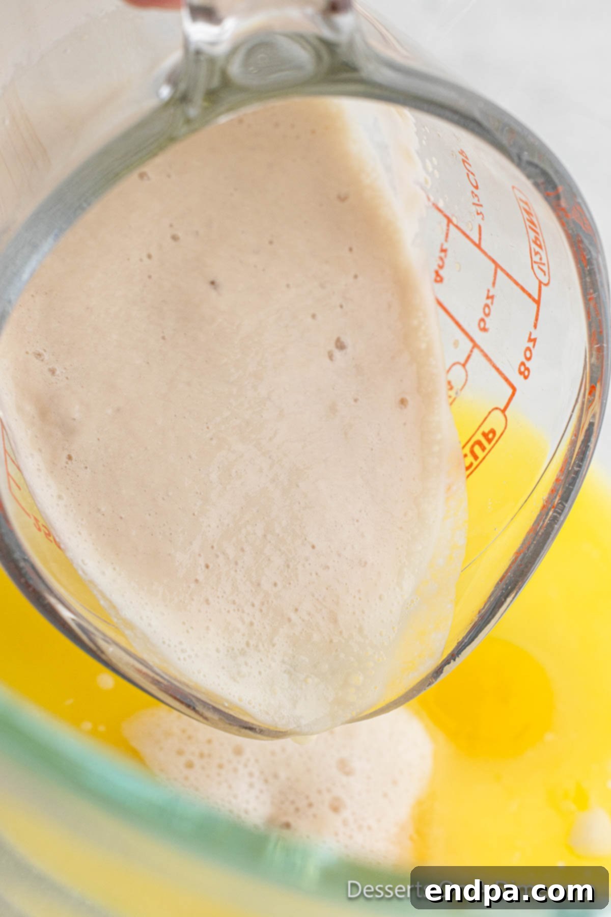 The yeast mixture showing small bubbles and a slightly thickened consistency, indicating successful activation.