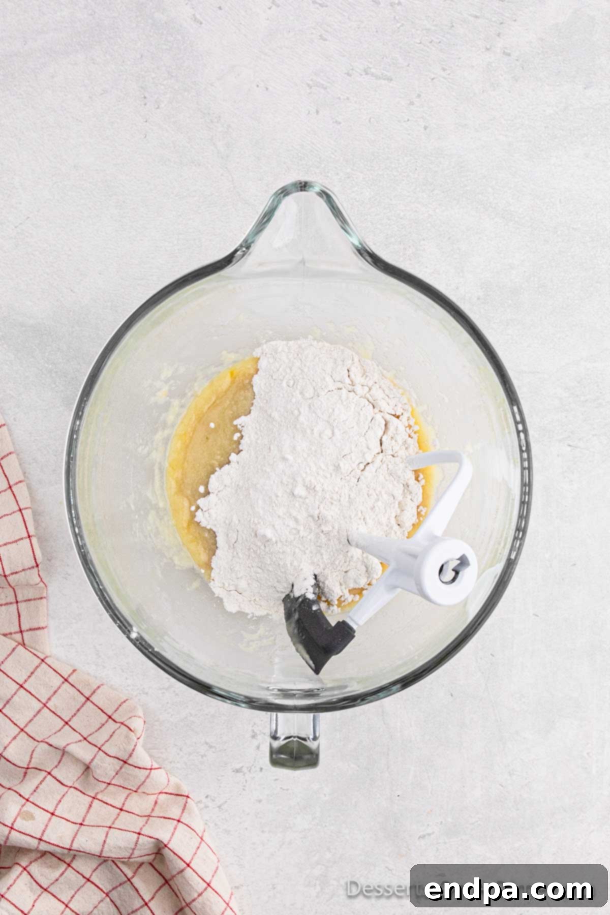 A stand mixer bowl containing flour and the activated yeast mixture, ready for the dough to be kneaded.