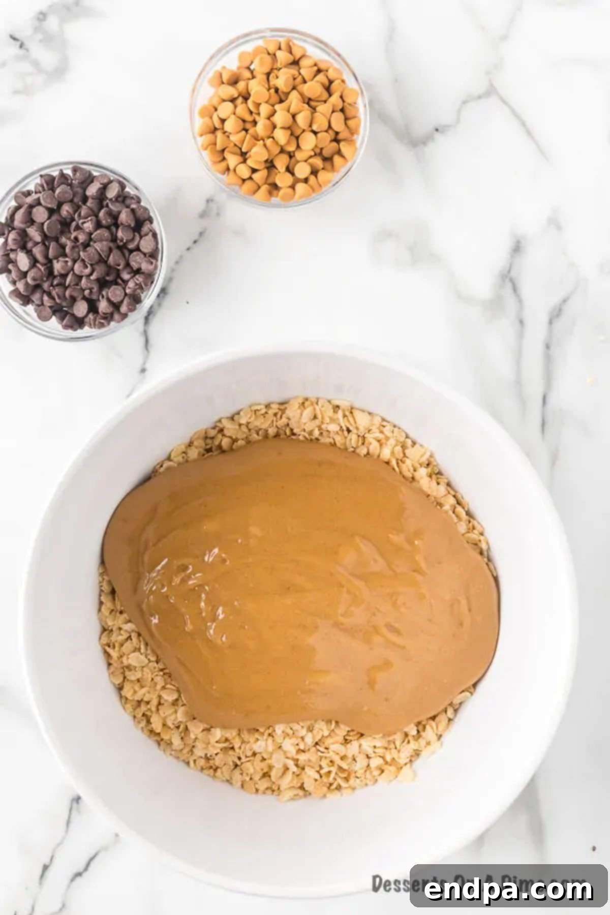 A large mixing bowl containing Rice Krispies cereal, now thoroughly coated with the warm, shiny peanut butter, sugar, and corn syrup mixture, ready for the pan.