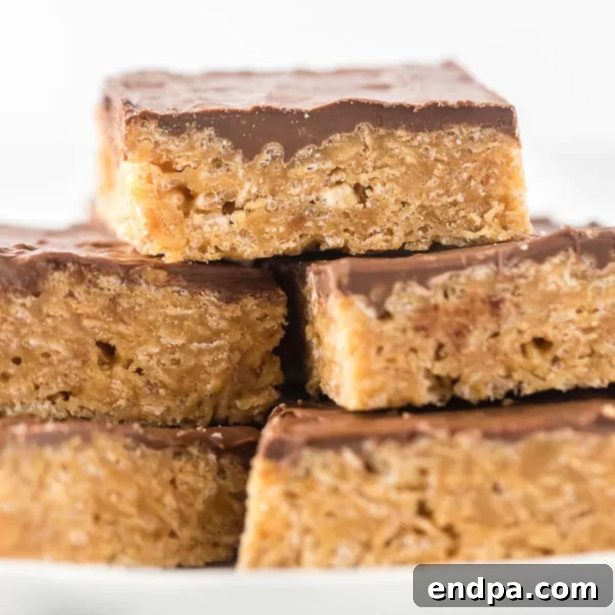 A close-up of a perfectly cut Scotcheroo bar with a glossy chocolate and butterscotch topping.