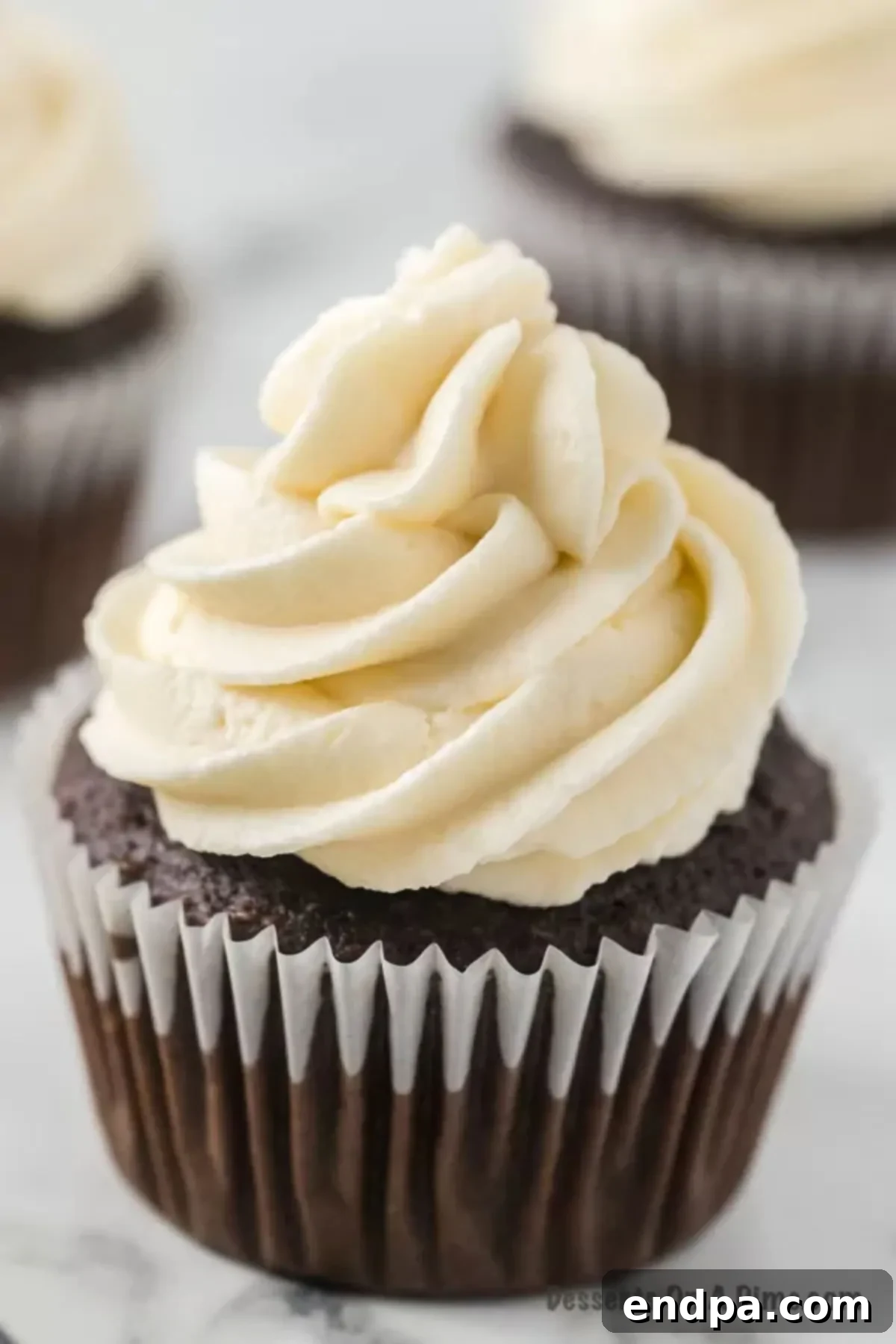 Close up of a chocolate cupcake topped with homemade marshmallow frosting, showcasing its fluffy texture.