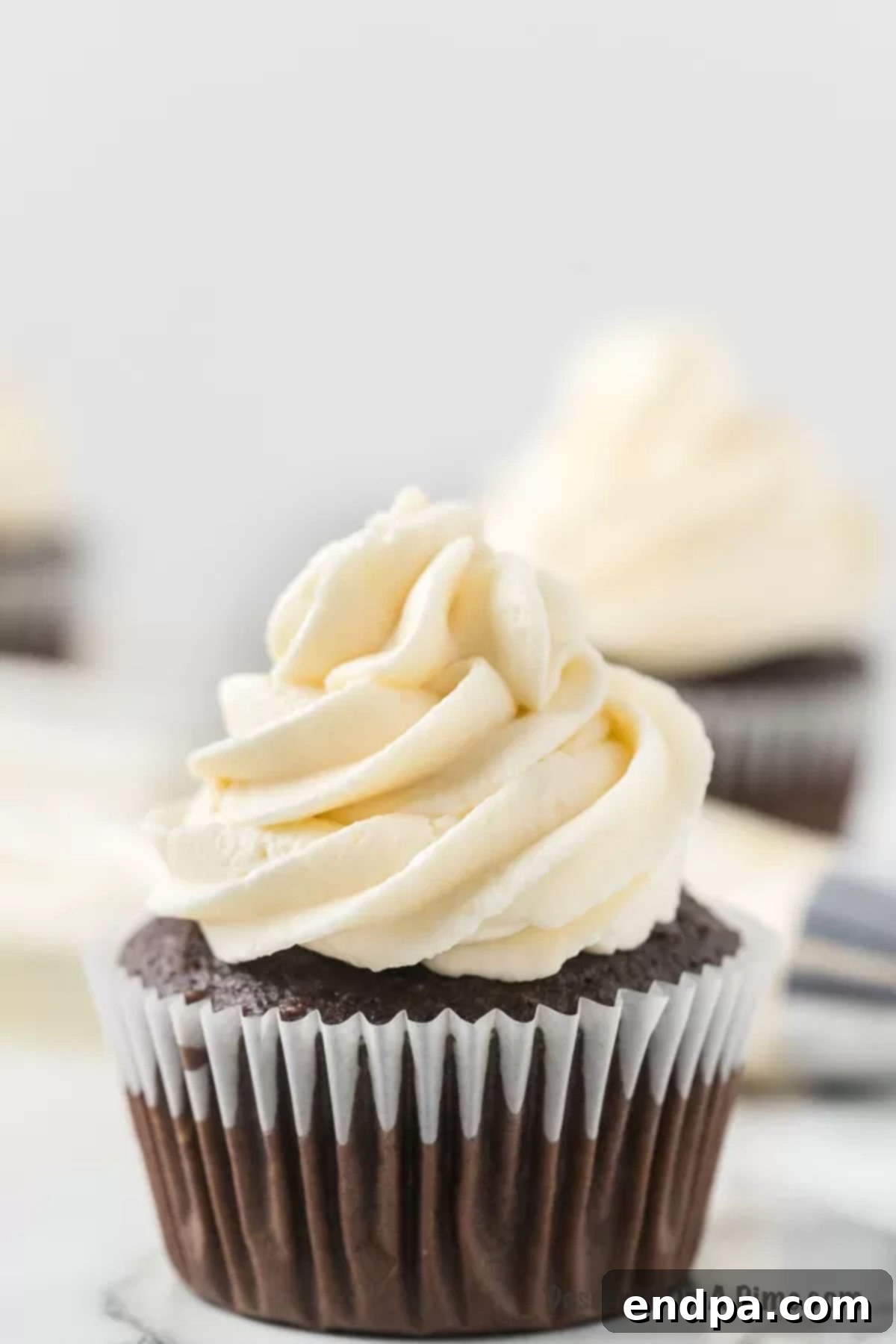 Close up of a chocolate cupcake topped with perfectly piped homemade marshmallow frosting, ready to be enjoyed.