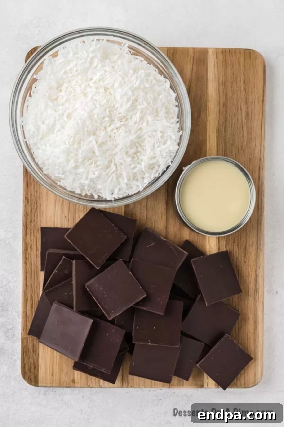 Decadent Homemade Mounds Bars 3 Ingredients for Mounds Bars laid out: Shredded Coconut, a can of sweetened condensed milk, and chocolate bars.