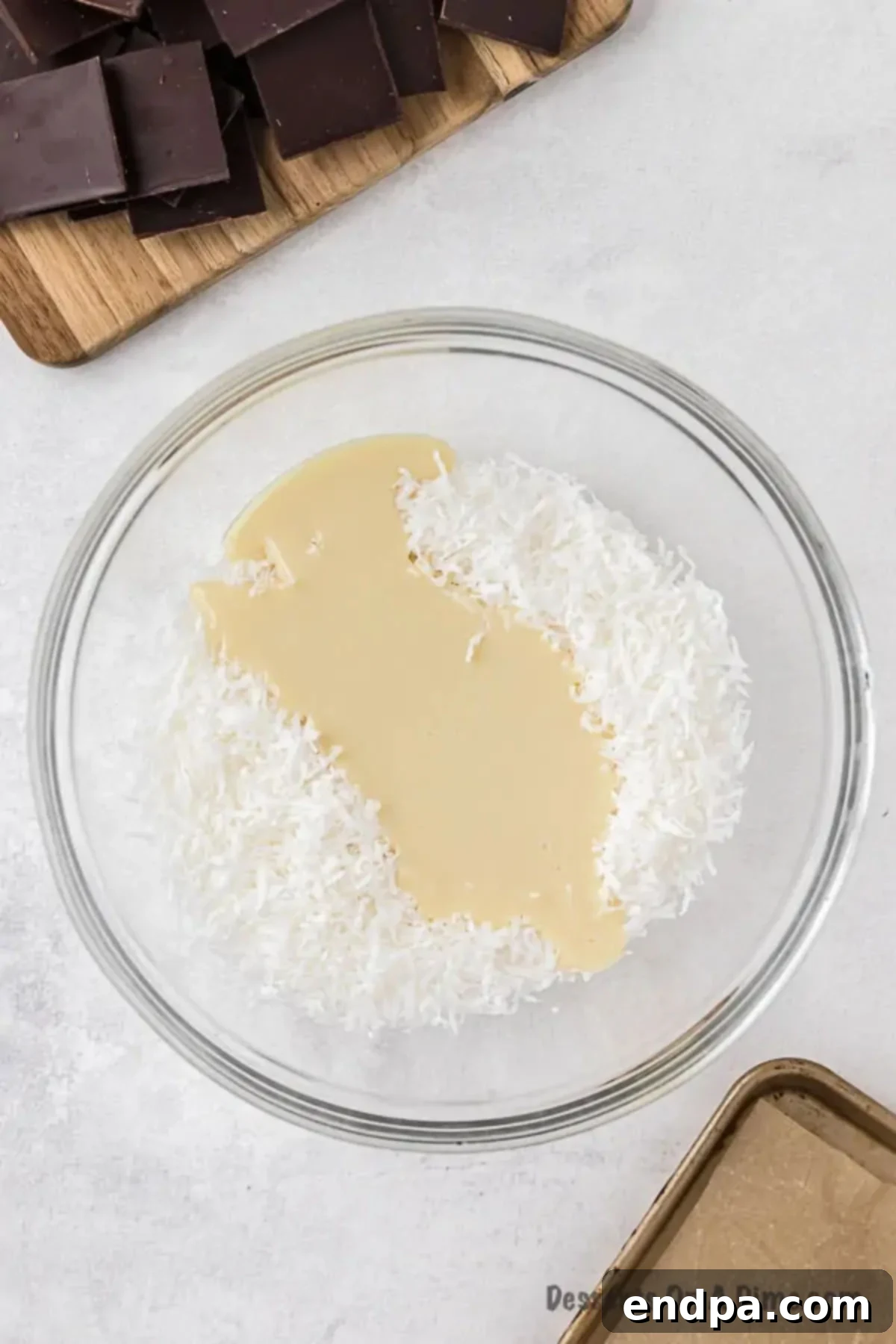 Decadent Homemade Mounds Bars 4 Bowl of shredded coconut and sweetened condensed milk ready to be mixed.