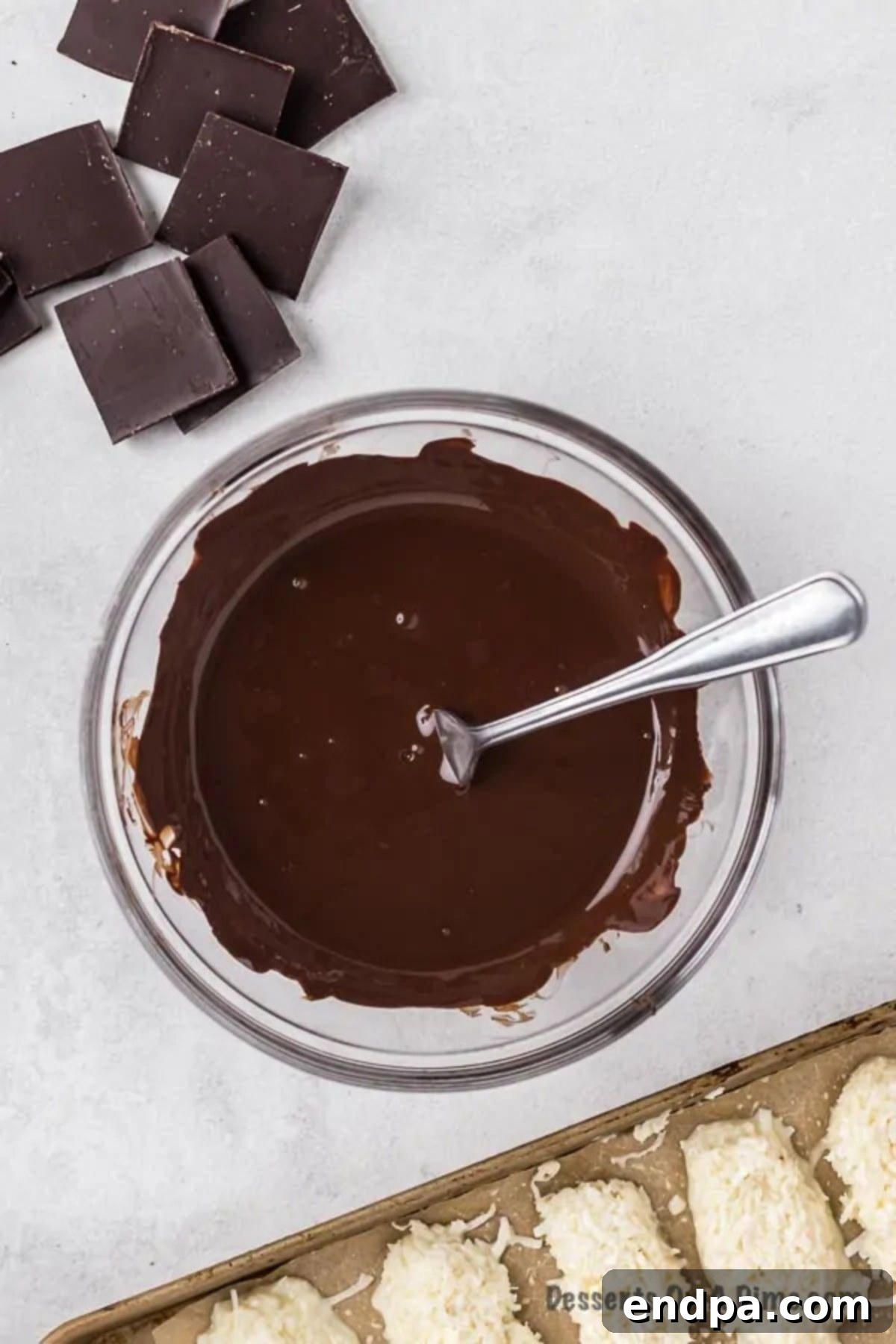 Decadent Homemade Mounds Bars 8 Melted chocolate being stirred smoothly in a bowl.