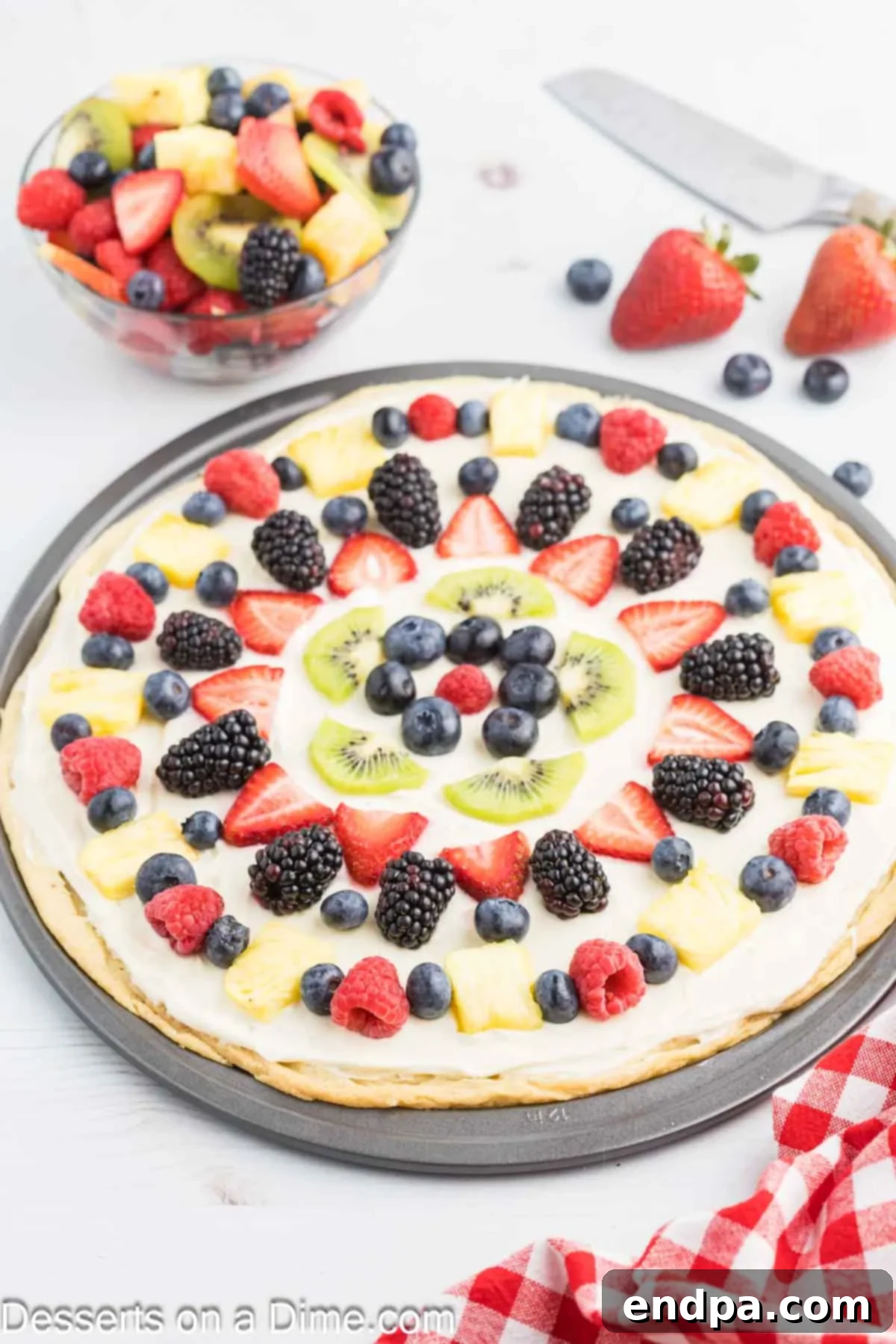 Fresh Fruit Fiesta Pizza 2 A beautifully arranged Fruit Pizza featuring a golden sugar cookie crust, creamy white frosting, and a vibrant assortment of fresh strawberries, blueberries, kiwi, and pineapple.