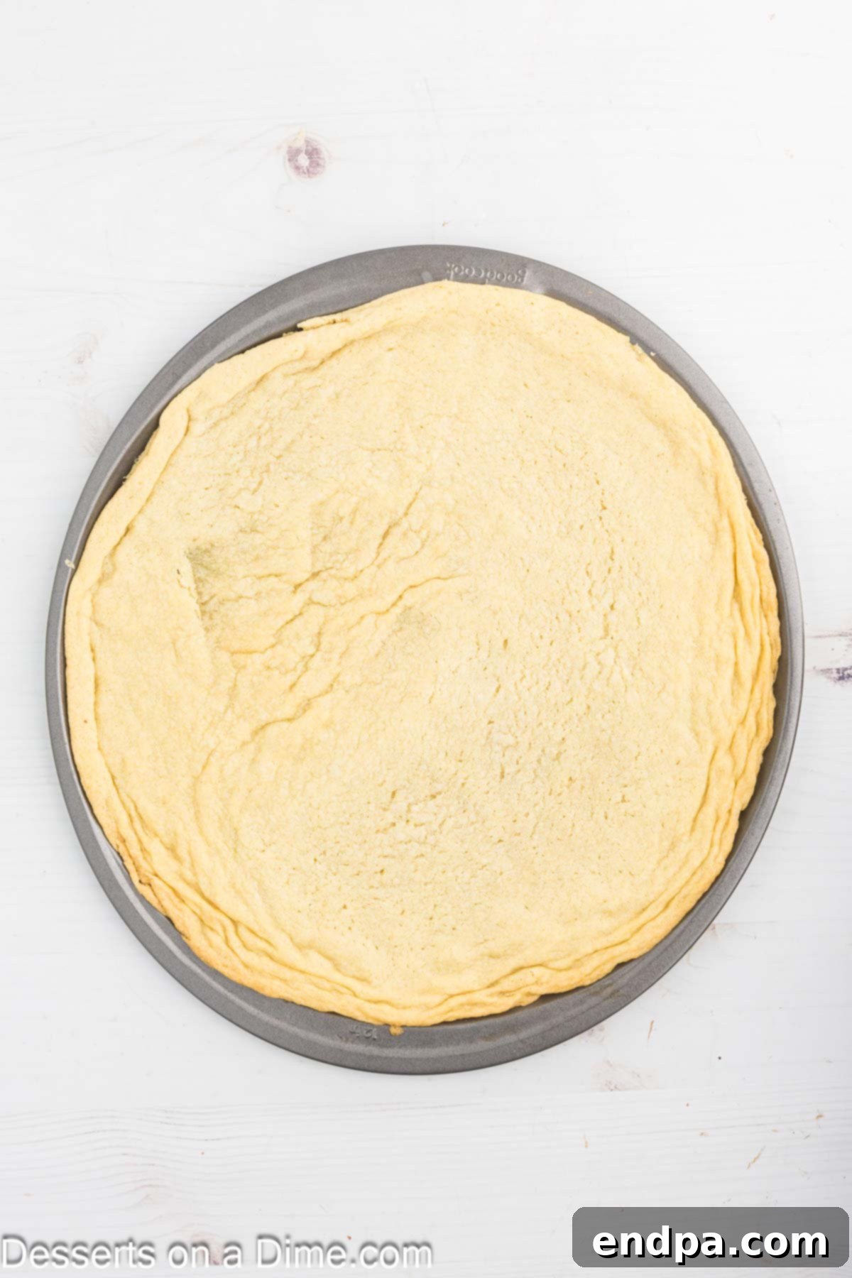 Fresh Fruit Fiesta Pizza 4 Sugar cookie dough evenly spread across a 12-inch pizza pan, ready for baking.