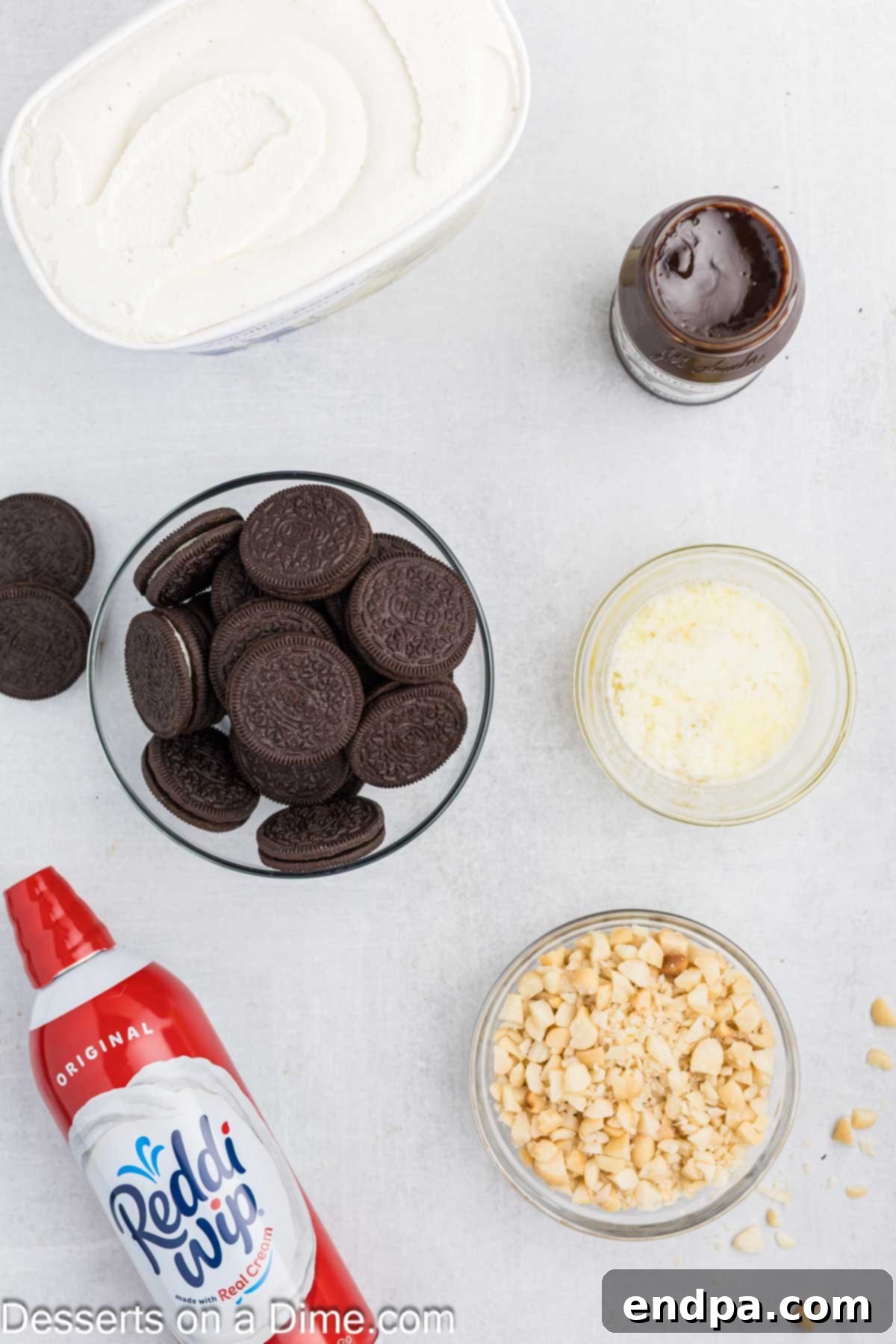 Hula Pie 3 A flat lay image of all essential ingredients for Hula Pie: Oreo cookies, butter, vanilla ice cream, macadamia nuts, hot fudge, and whipped topping.