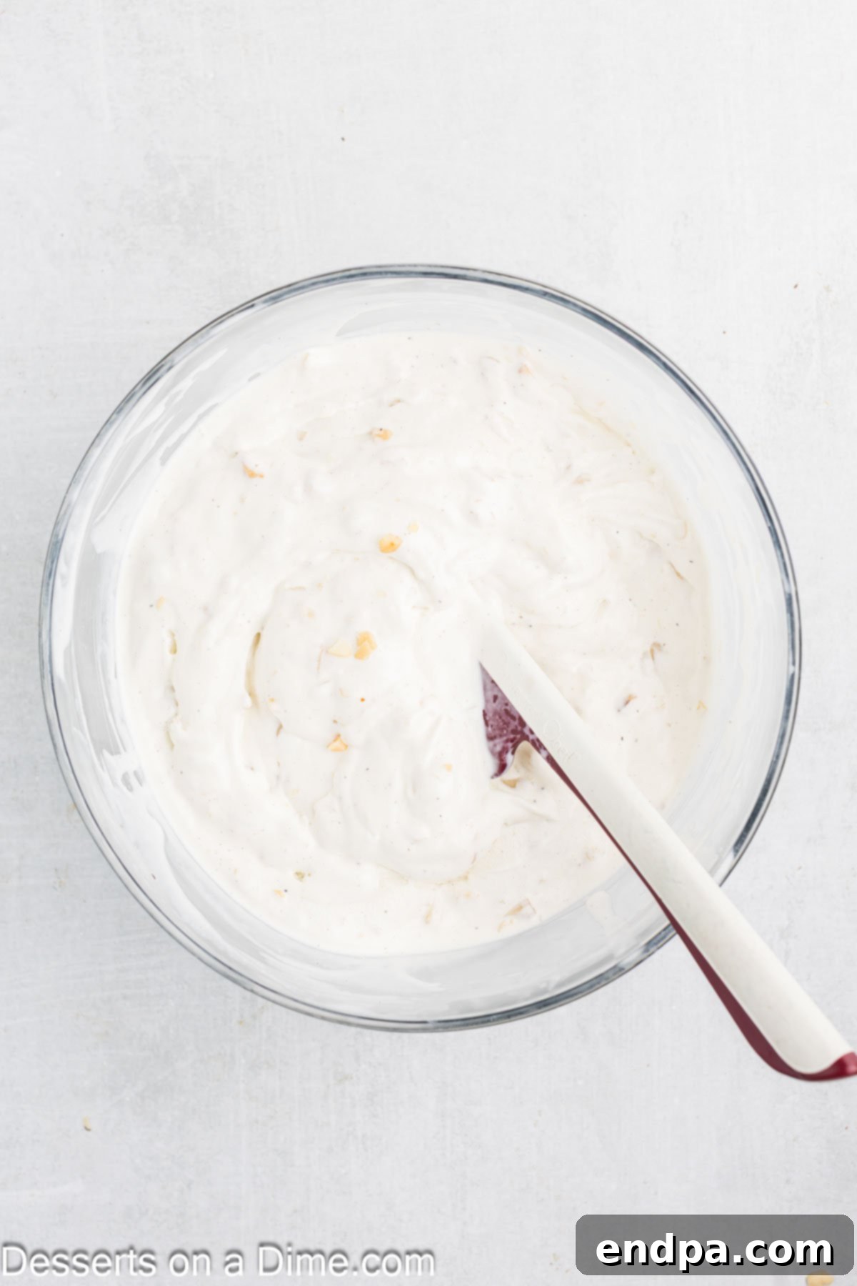 Hula Pie 6 Softened vanilla ice cream mixed with chopped macadamia nuts in a bowl.