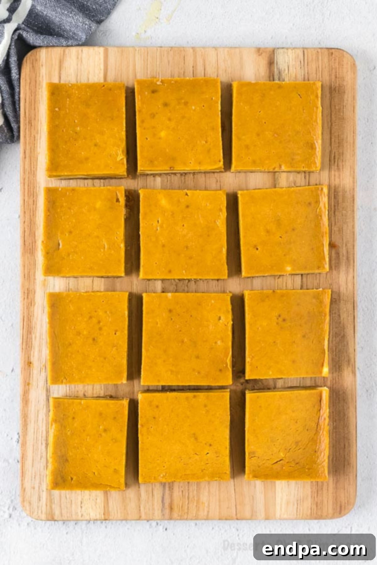 Spiced Pumpkin Cheesecake Bars 11 Pumpkin Cheesecake bars cut into slices on a cutting board