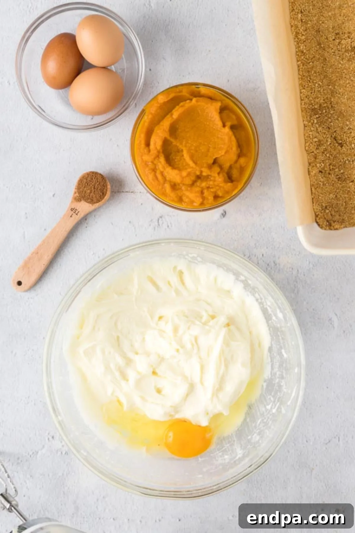 Spiced Pumpkin Cheesecake Bars 7 The eggs being mixed into the mix bowl with the cream cheese and the sugar already combined and fluffy.