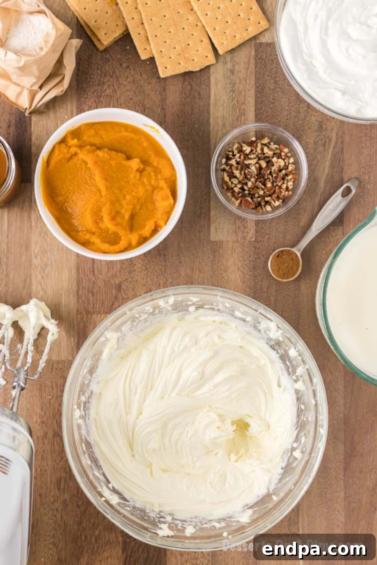Cream cheese and sugar are being beaten together vigorously in a large mixing bowl, creating a light and fluffy texture, ready for the next step of the Pumpkin Lasagna recipe.