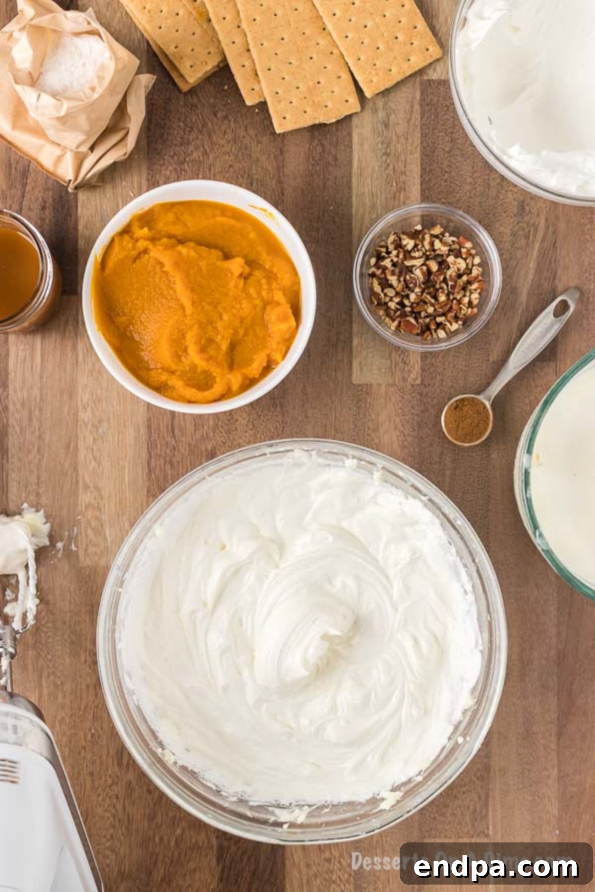 The cool whip is being carefully folded into the cream cheese mixture in a large mixing bowl with a spatula, ensuring a light and uniform consistency for the dessert layer.