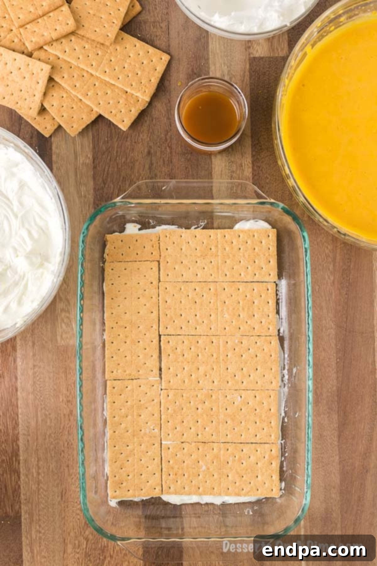 A layer of the prepared cream cheese mixture is spread evenly into the bottom of a 9x13 inch pan, with whole graham crackers meticulously arranged on top, forming the first base layer of the pumpkin lasagna.