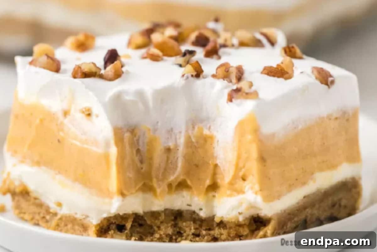 A perfectly sliced piece of Pumpkin Delight on a white plate, showcasing its distinct layers of crust, cream cheese, pumpkin, and whipped topping.