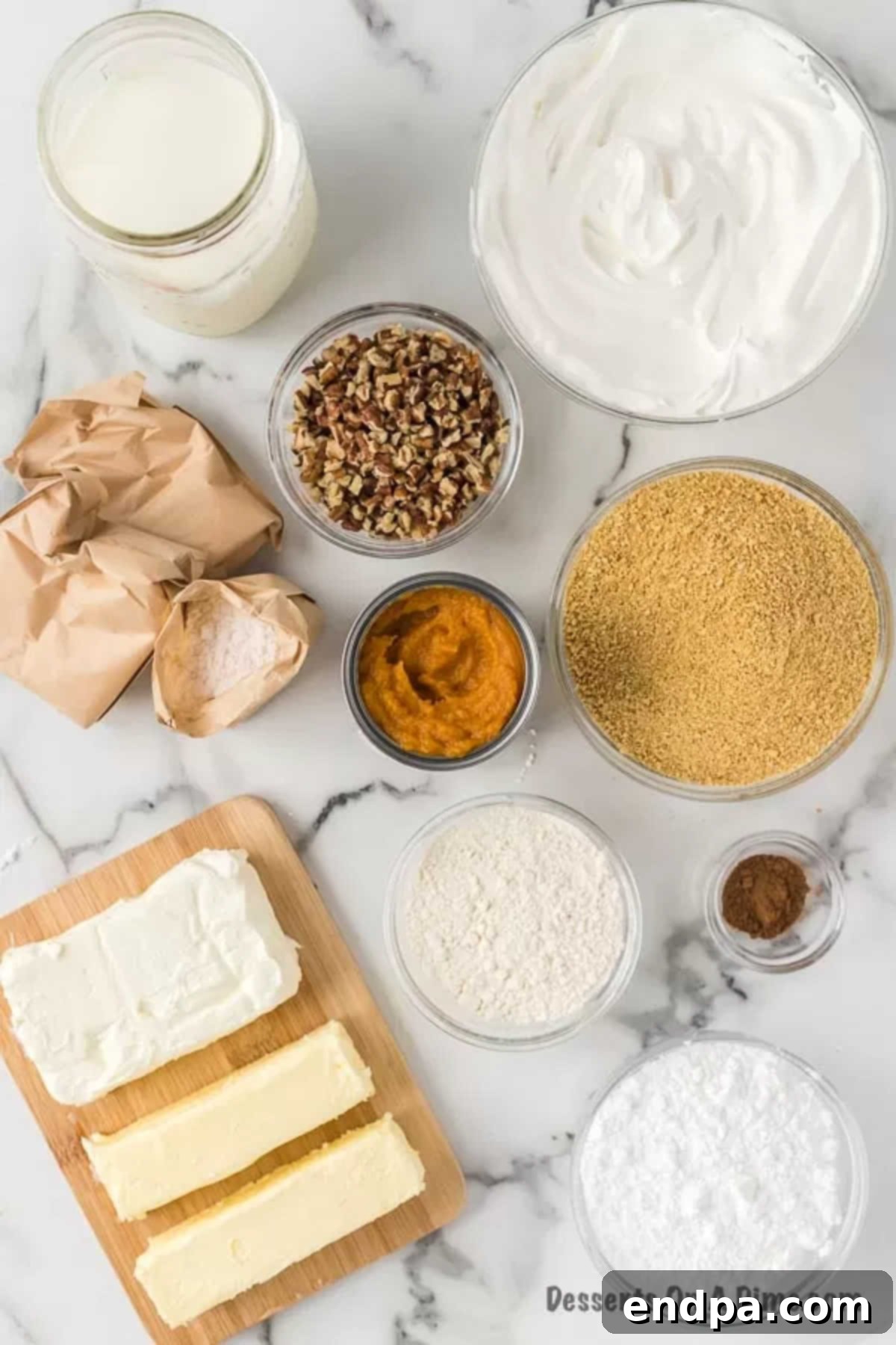 Ingredients for Pumpkin Delight arranged on a table: boxes of pudding mix, cream cheese, graham crackers, pecans, a tub of whipped cream, milk, canned pumpkin puree, and powdered sugar.