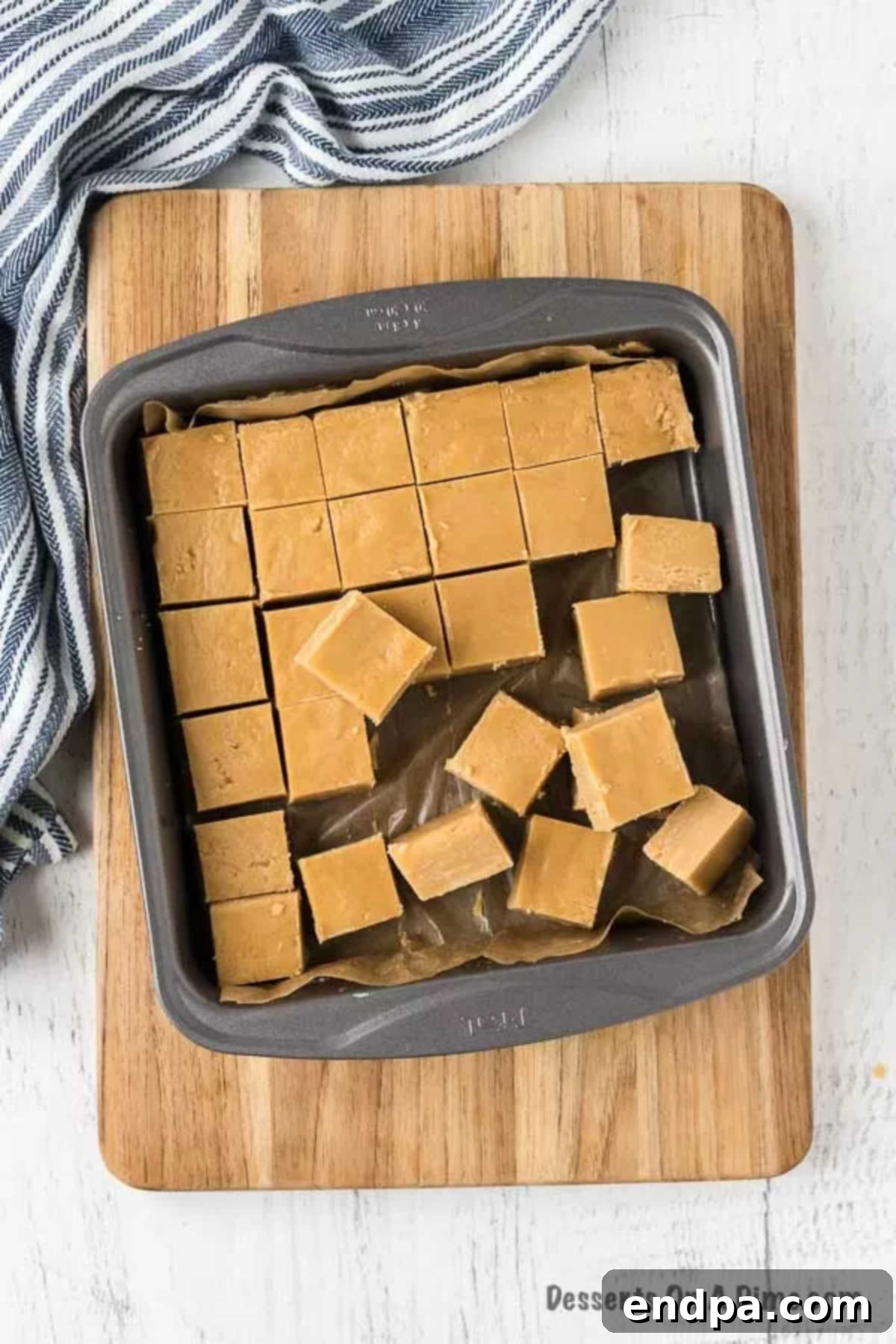 Individual squares of peanut butter fudge being lifted from the pan after cutting.