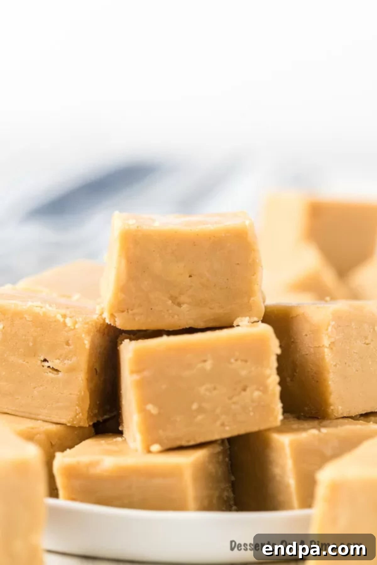 Stacked squares of creamy peanut butter fudge on a white platter, ready to be served or gifted.