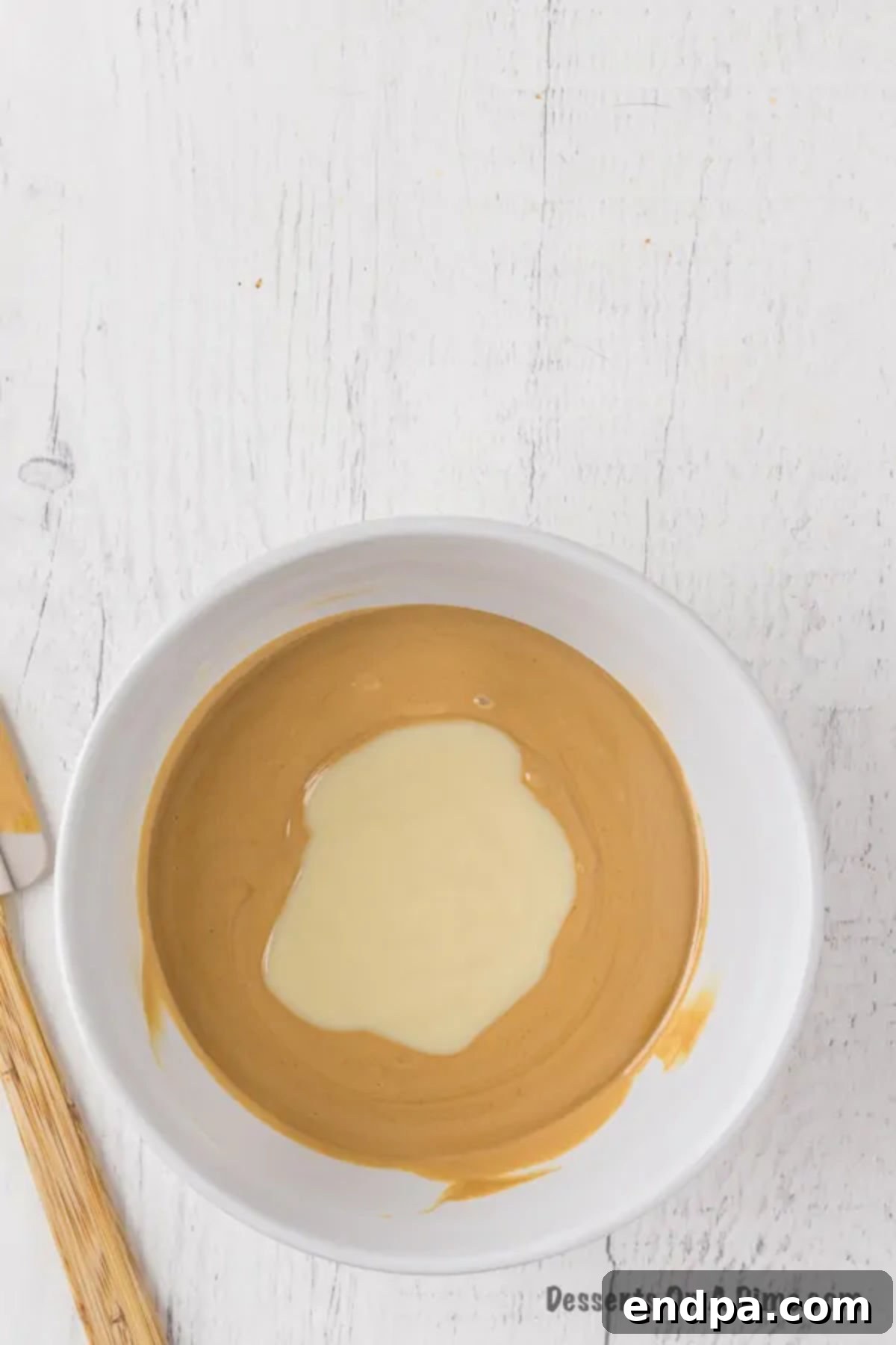 The fudge mixture being thoroughly combined in a bowl with a spatula.