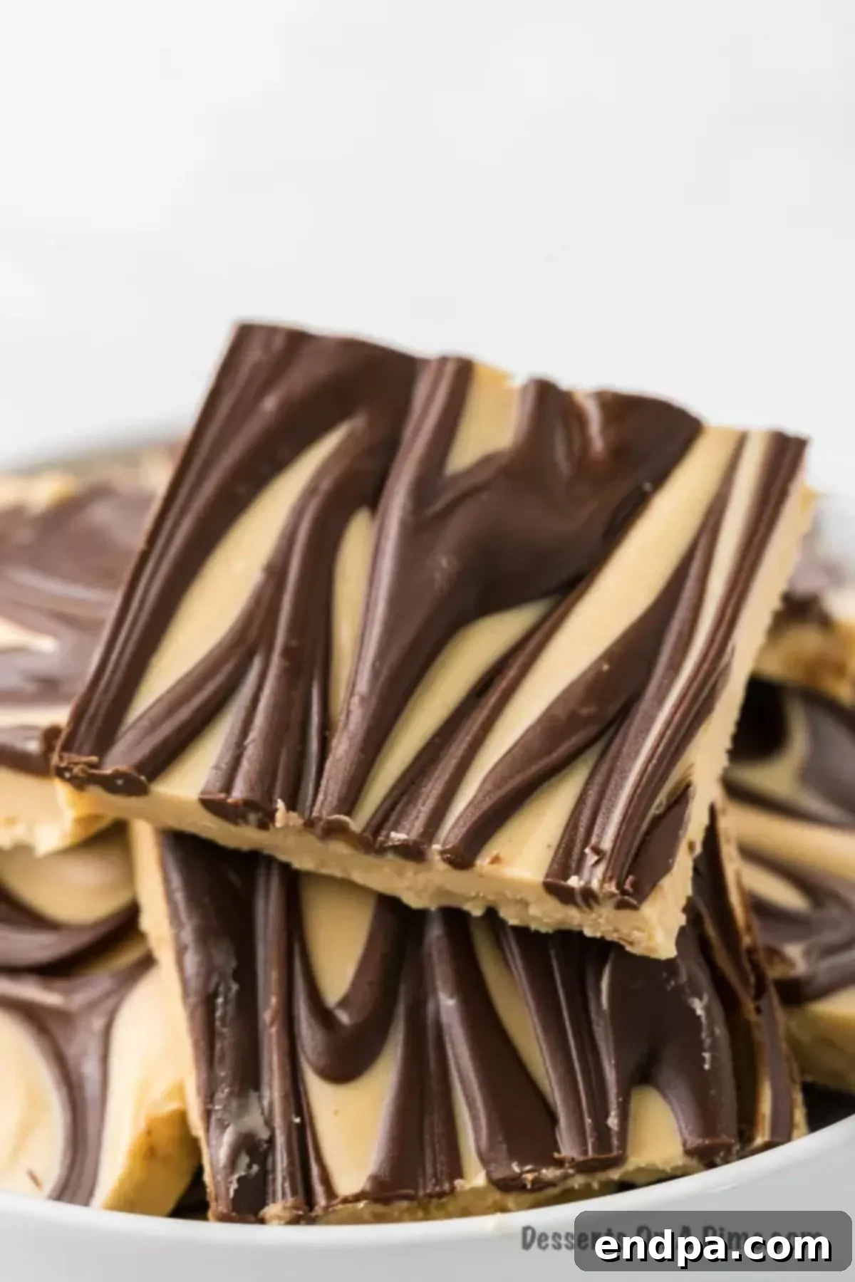 A serving bowl filled with perfectly cut and stacked squares of Tiger Butter Fudge, ready to be enjoyed