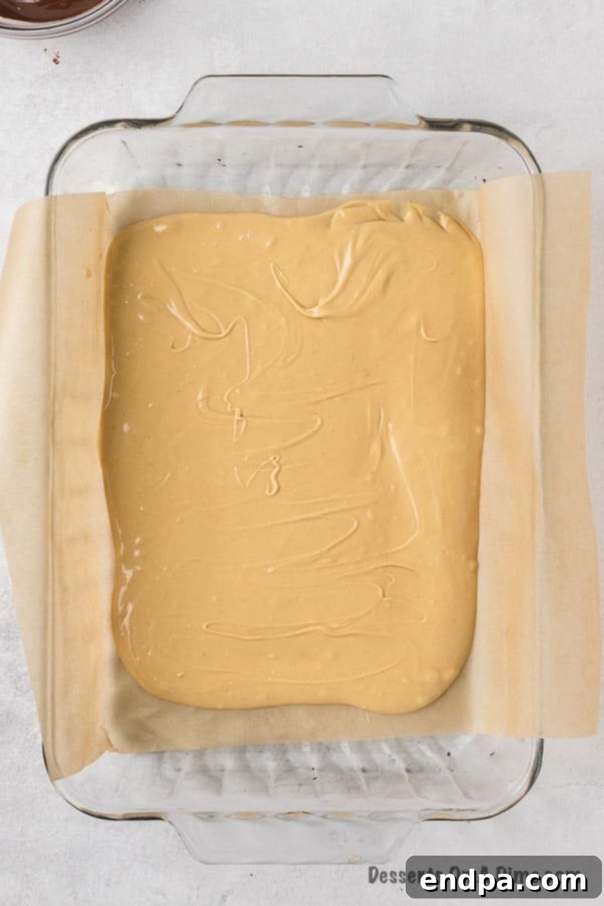 Spreading the vanilla-peanut butter mixture evenly into the parchment-lined baking dish