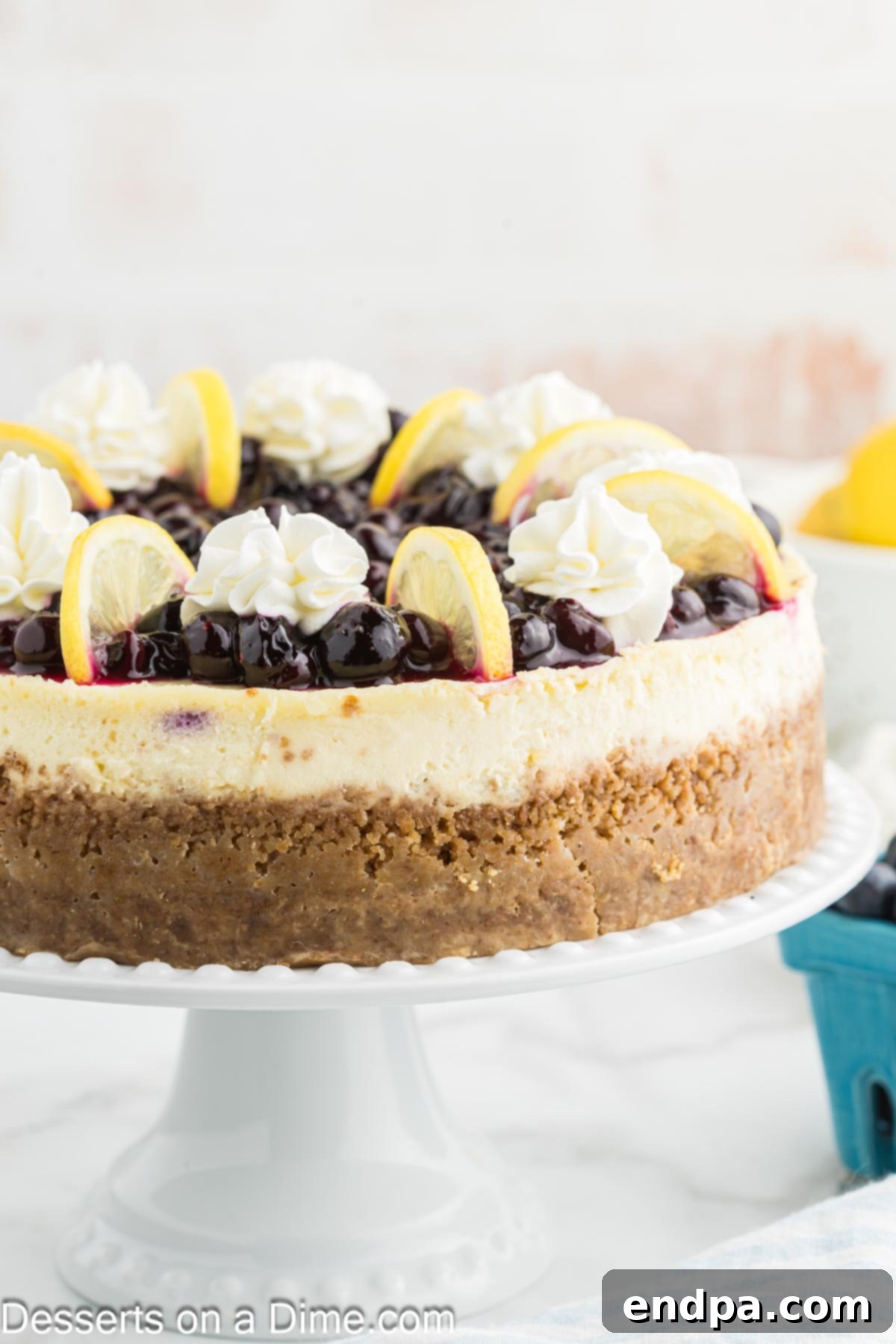 Heavenly Lemon Blueberry Cheesecake 12 A close-up shot of a single slice of Lemon Blueberry Cheesecake on a white plate, showcasing its creamy texture, graham cracker crust, and a generous layer of blueberry topping.