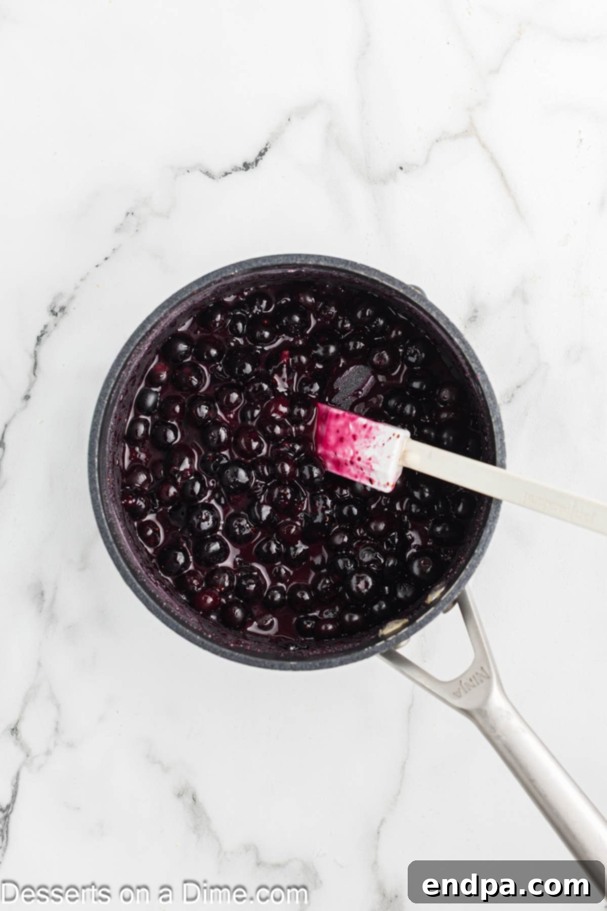 Heavenly Lemon Blueberry Cheesecake 10 Fresh blueberries simmering in a saucepan with sugar and cornstarch, forming a thick, glossy topping.