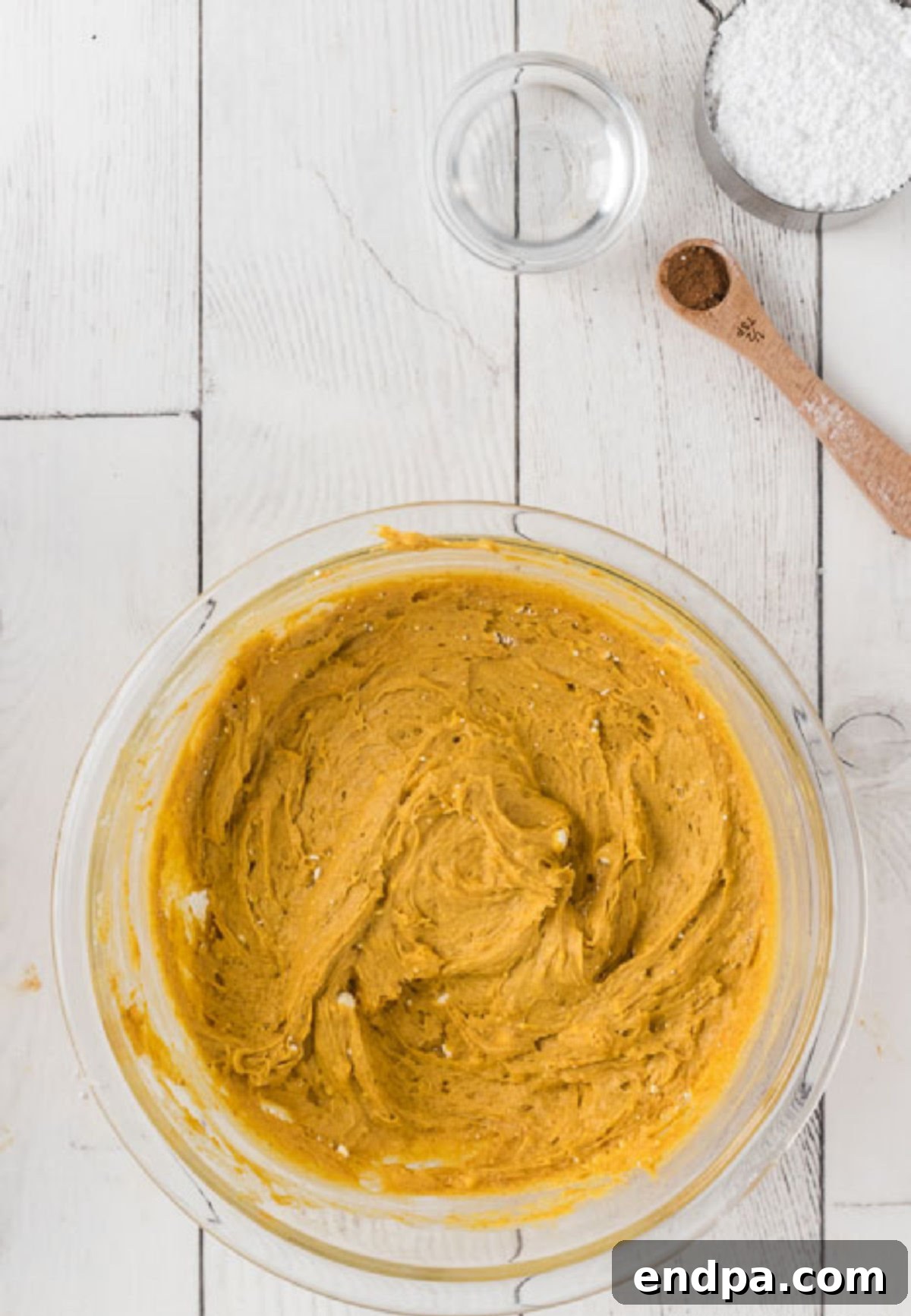 The cake mix, pumpkin puree, and pumpkin pie spice blended together in a large mixing bowl, showing a smooth, orange batter.
