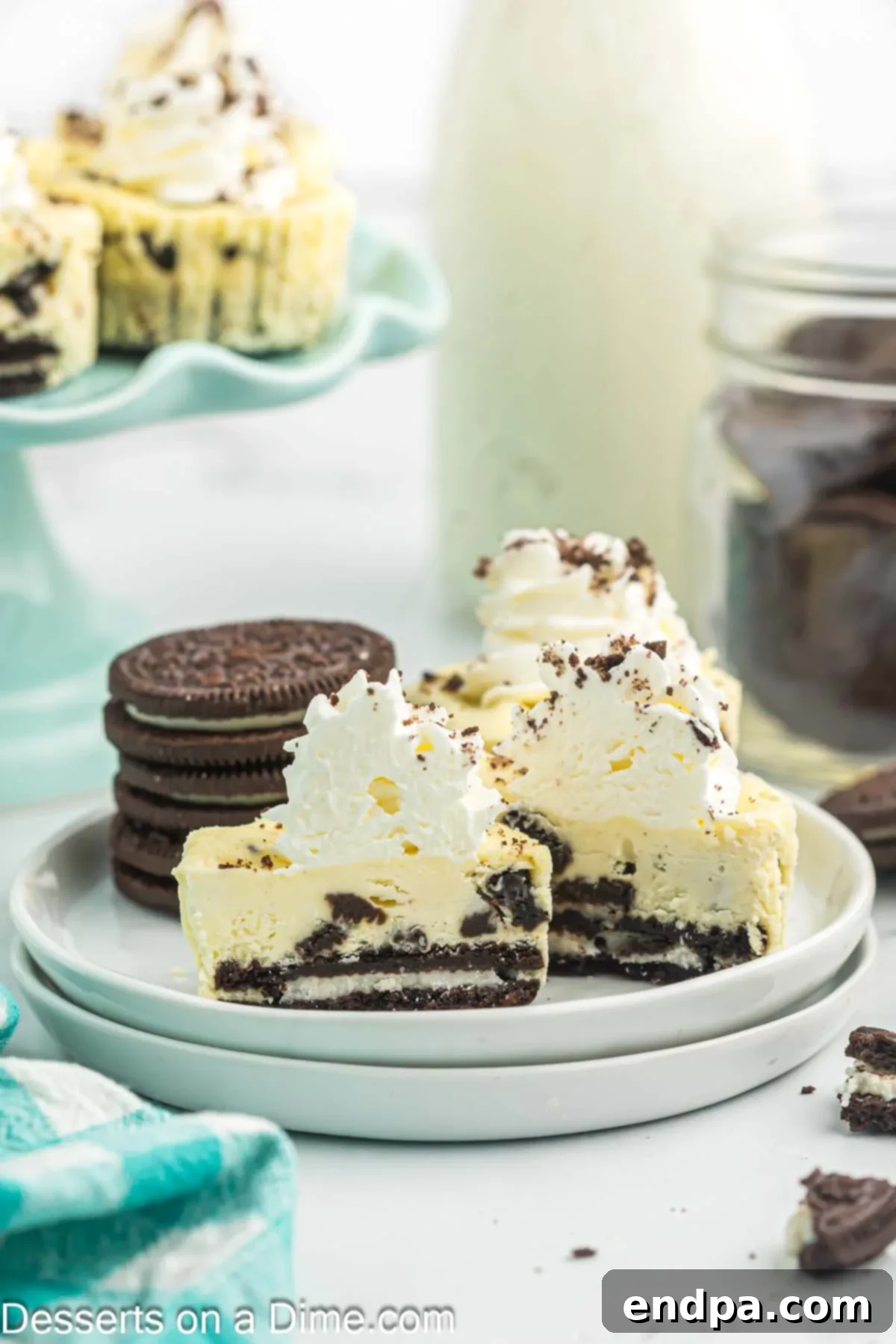 Delicious cheesecake bites garnished with whipped cream and Oreo crumbs on a plate.