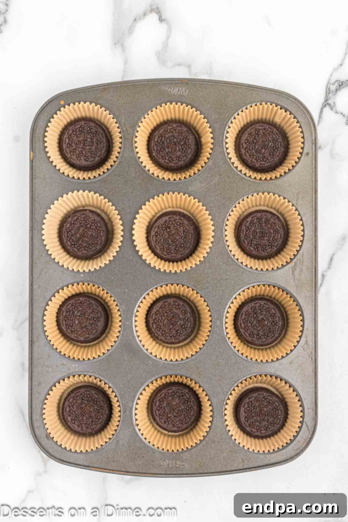 A whole Oreo cookie placed into a paper cupcake liner in a muffin tin, forming the crust.