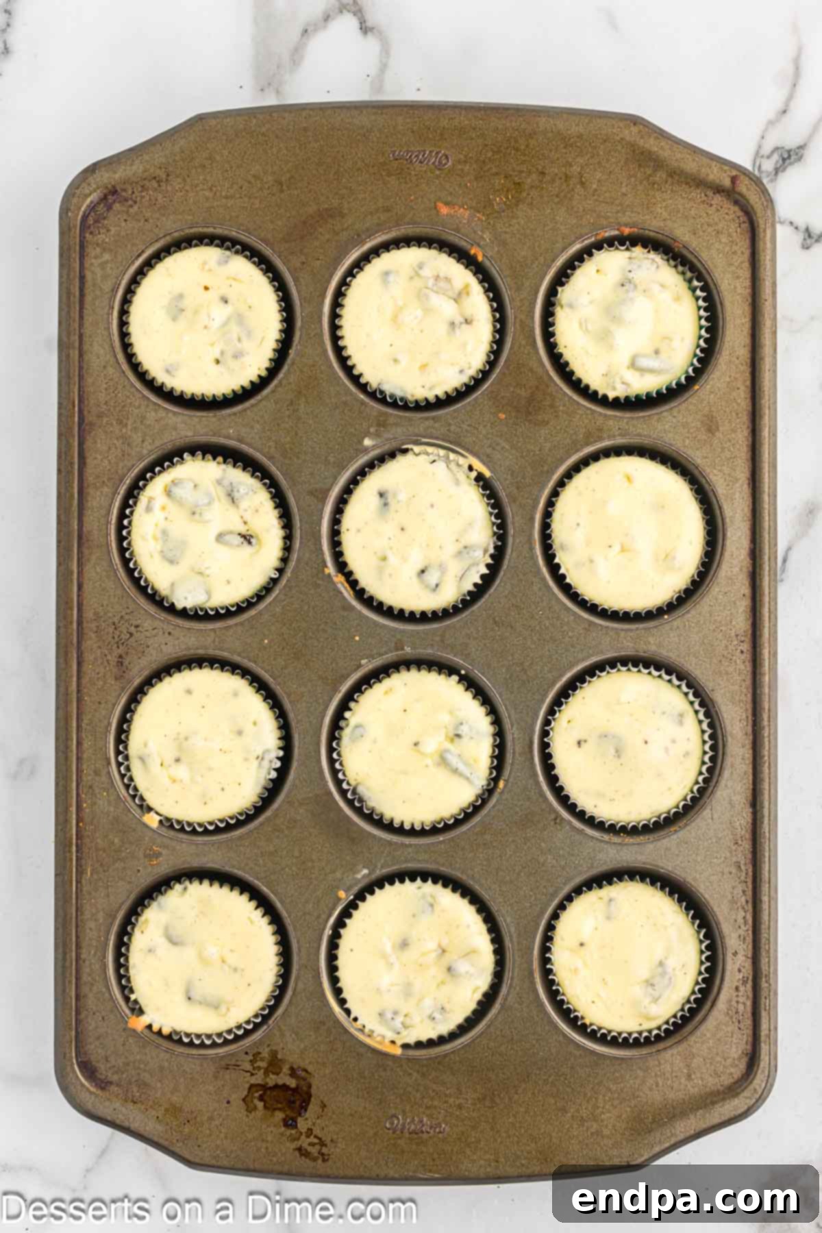 Baked mini cheesecakes cooling in the muffin pan after being removed from the oven.