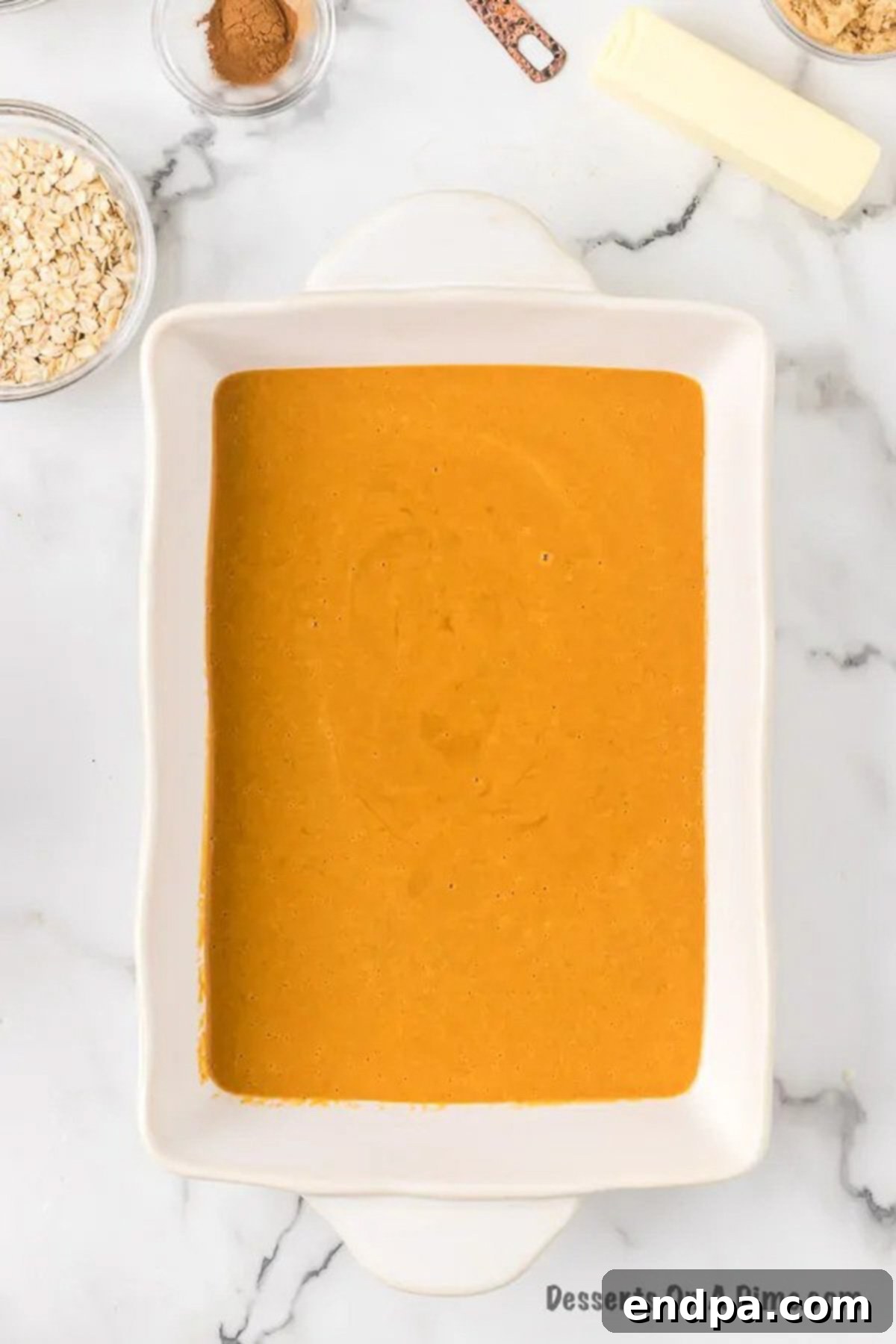 Autumn Pumpkin Crumble 6 Pumpkin mixture being poured and spread evenly into the prepared 9x13 baking dish.