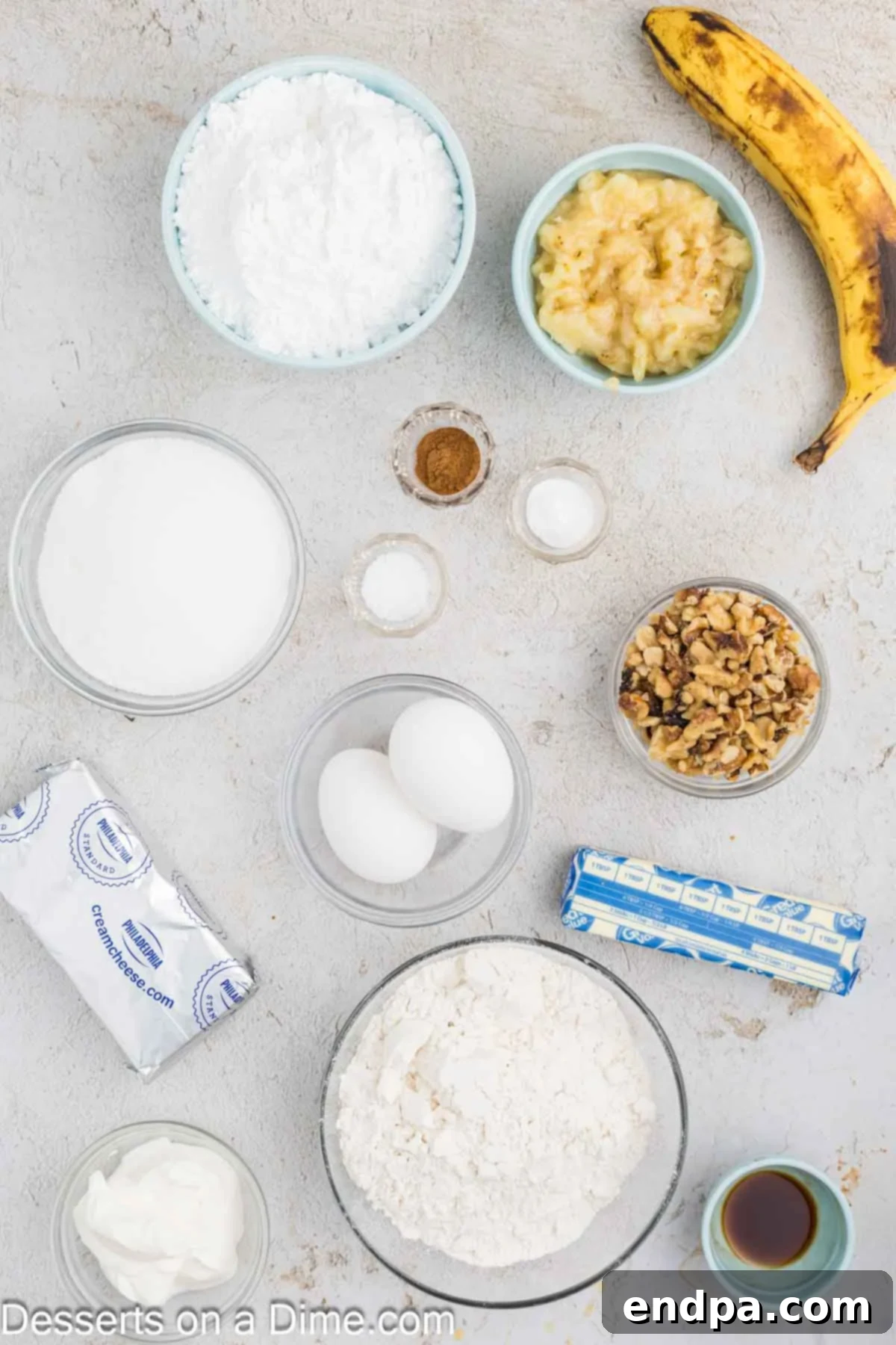 Ultimate Banana Bars 3 Ingredients for banana bars - flour, cinnamon, baking soda, salt, butter, sugar, eggs, sour cream, bananas, walnuts, cream cheese, vanilla, powdered sugar arranged on a rustic wooden surface.