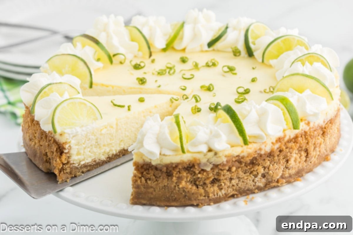 A slice of Key Lime Cheesecake on a white plate, topped with whipped cream and a lime wedge.