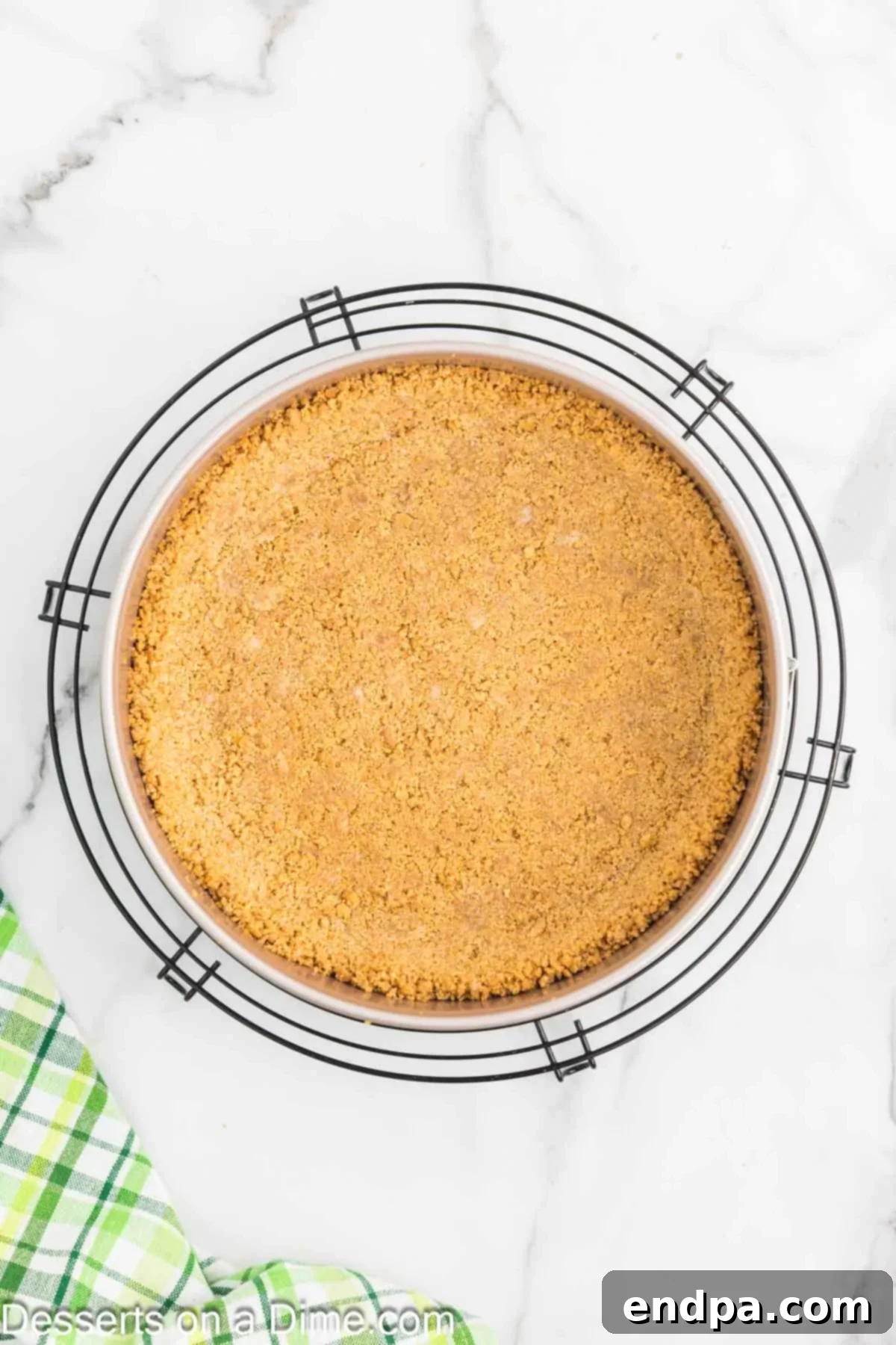 Baked graham cracker crust cooling in a springform pan.