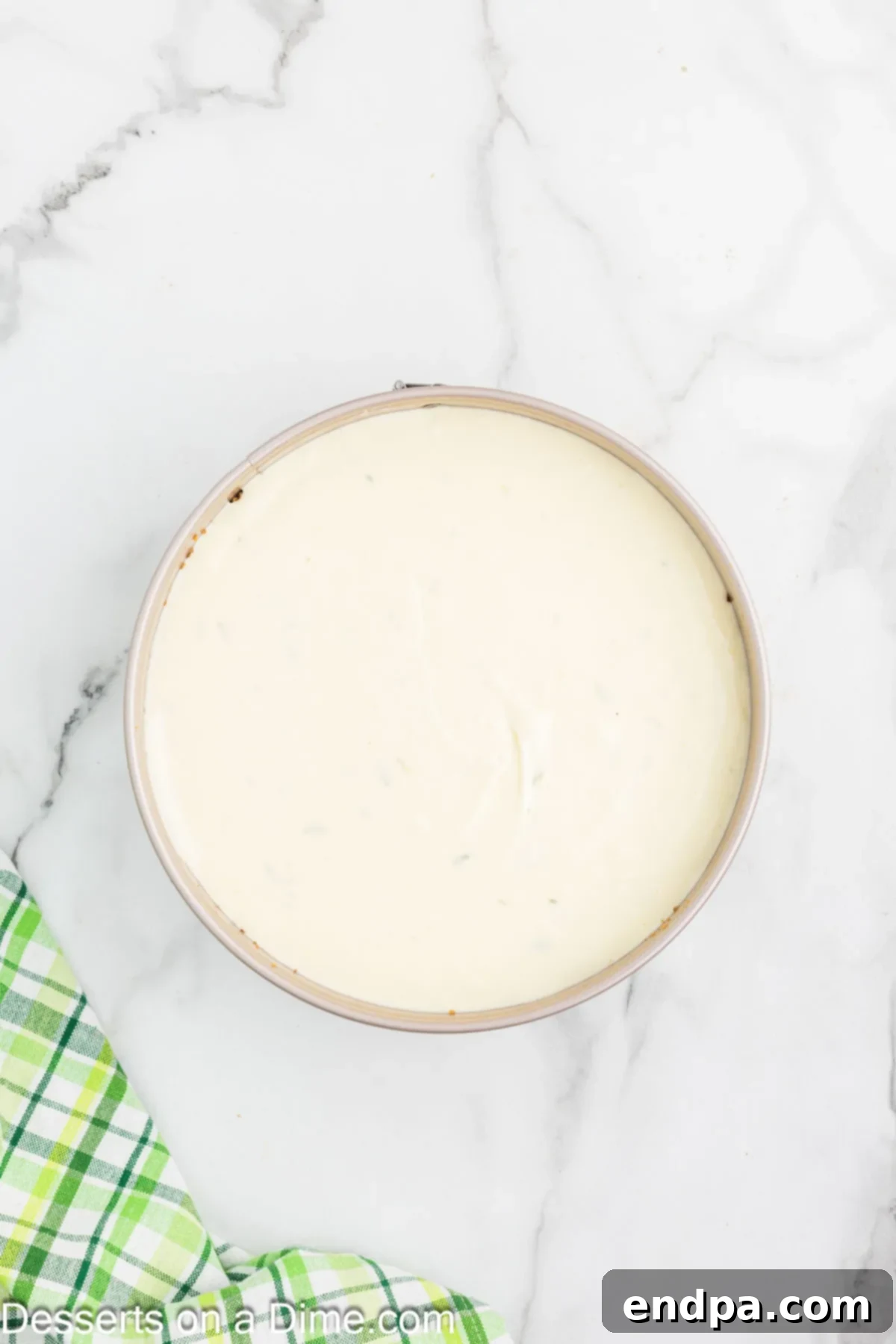 Cream cheese filling poured into the graham cracker crust in a springform pan.