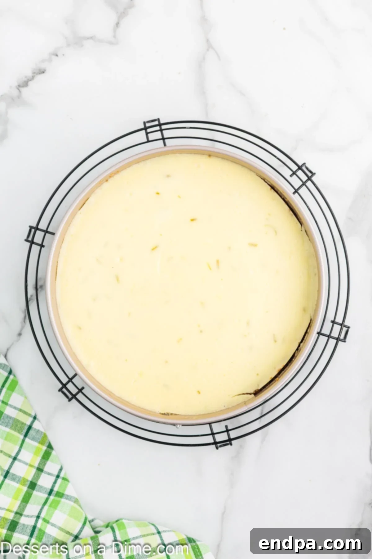 Baked Key Lime Cheesecake cooling on a wire rack after being removed from the oven.
