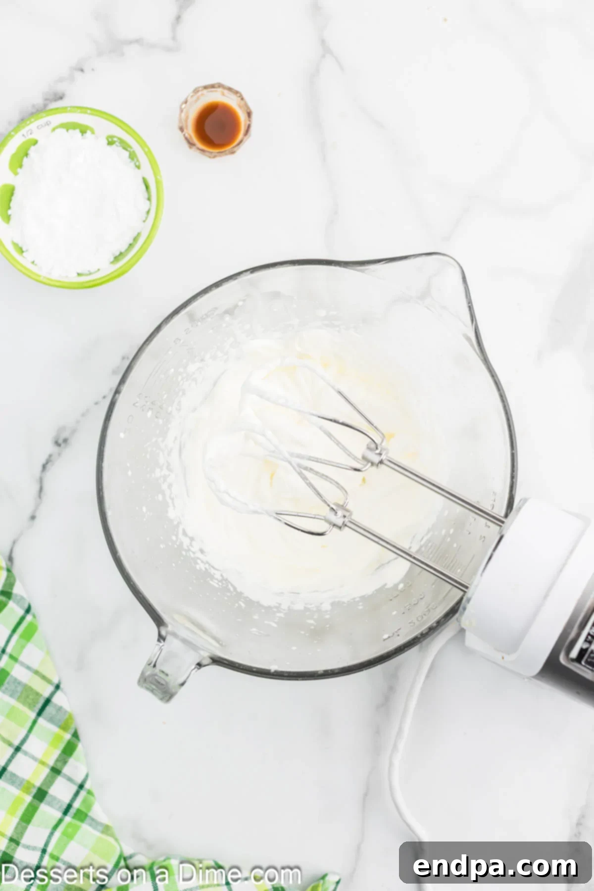 Heavy cream being whipped in a mixing bowl with an electric mixer for the cheesecake topping.